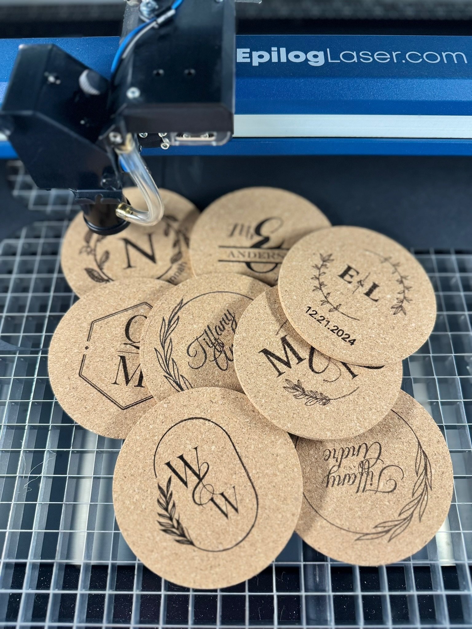 Laser engraving machine working on round kraft cork coasters with decorative text and patterns. #LaserEngraving