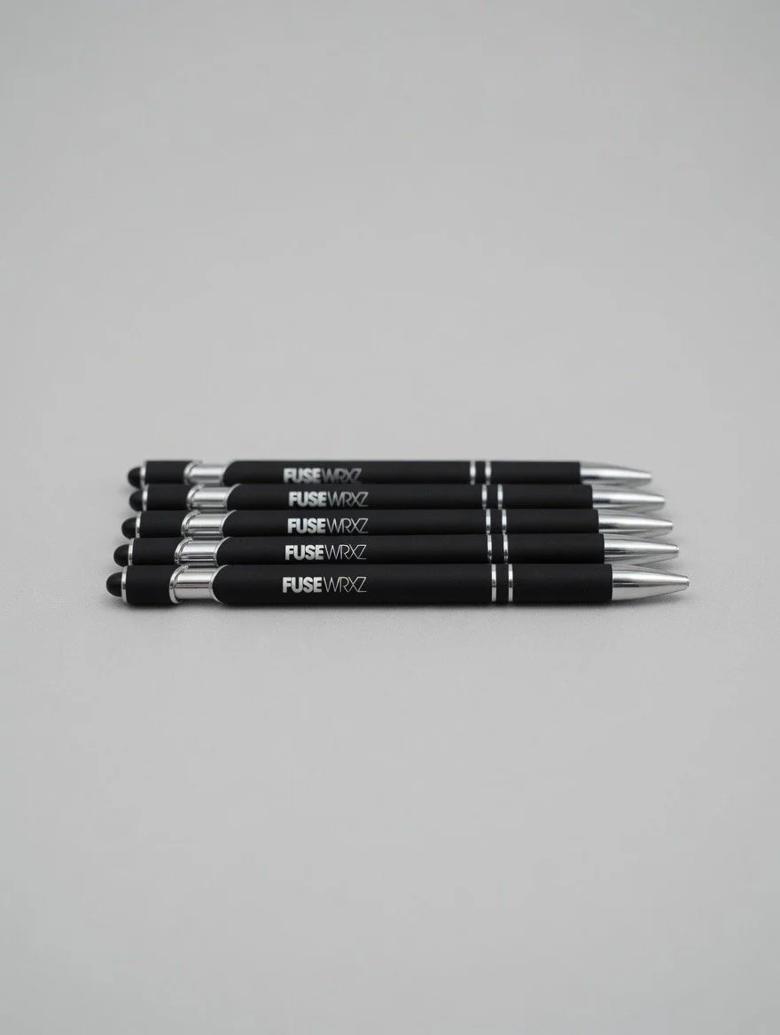 Six black pens with silver accents laid out horizontally on a plain gray background.