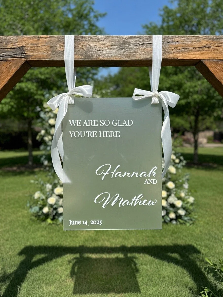Custom wedding sign. A white wedding sign hanging outdoors with text. Wedding Signage. Welcome Sign. Ceremony Sign. Wedding. Outdoor Ceremony. Ribbon.
