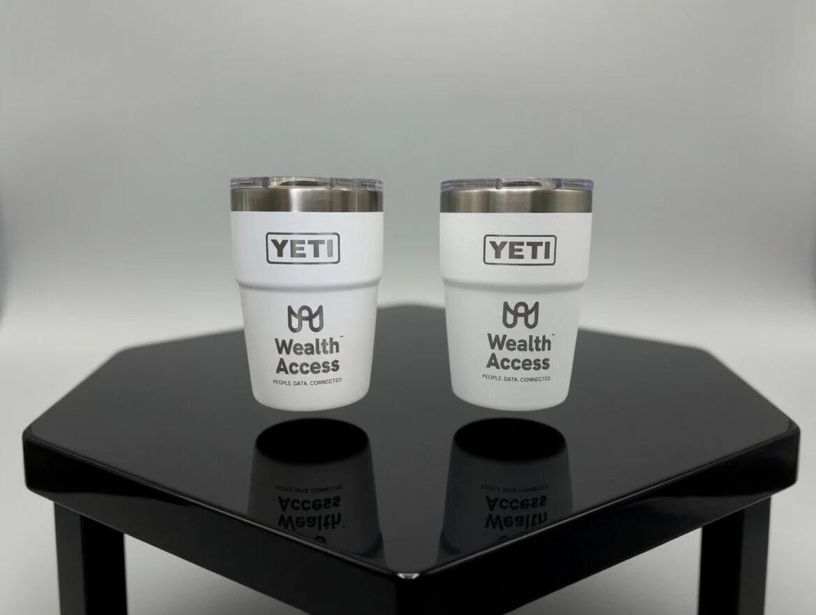 Two YETI insulated tumblers with black text, labeled 'Wealth Access,' placed on a glossy black table against a plain background. Custom logo engraving. 