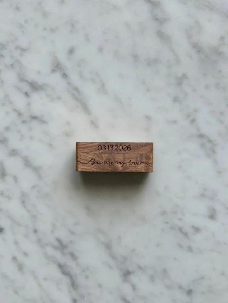 A small wooden block with the date 03.13.2026 and the phrase "You are my love" engraved on it, placed on a marble surface.
