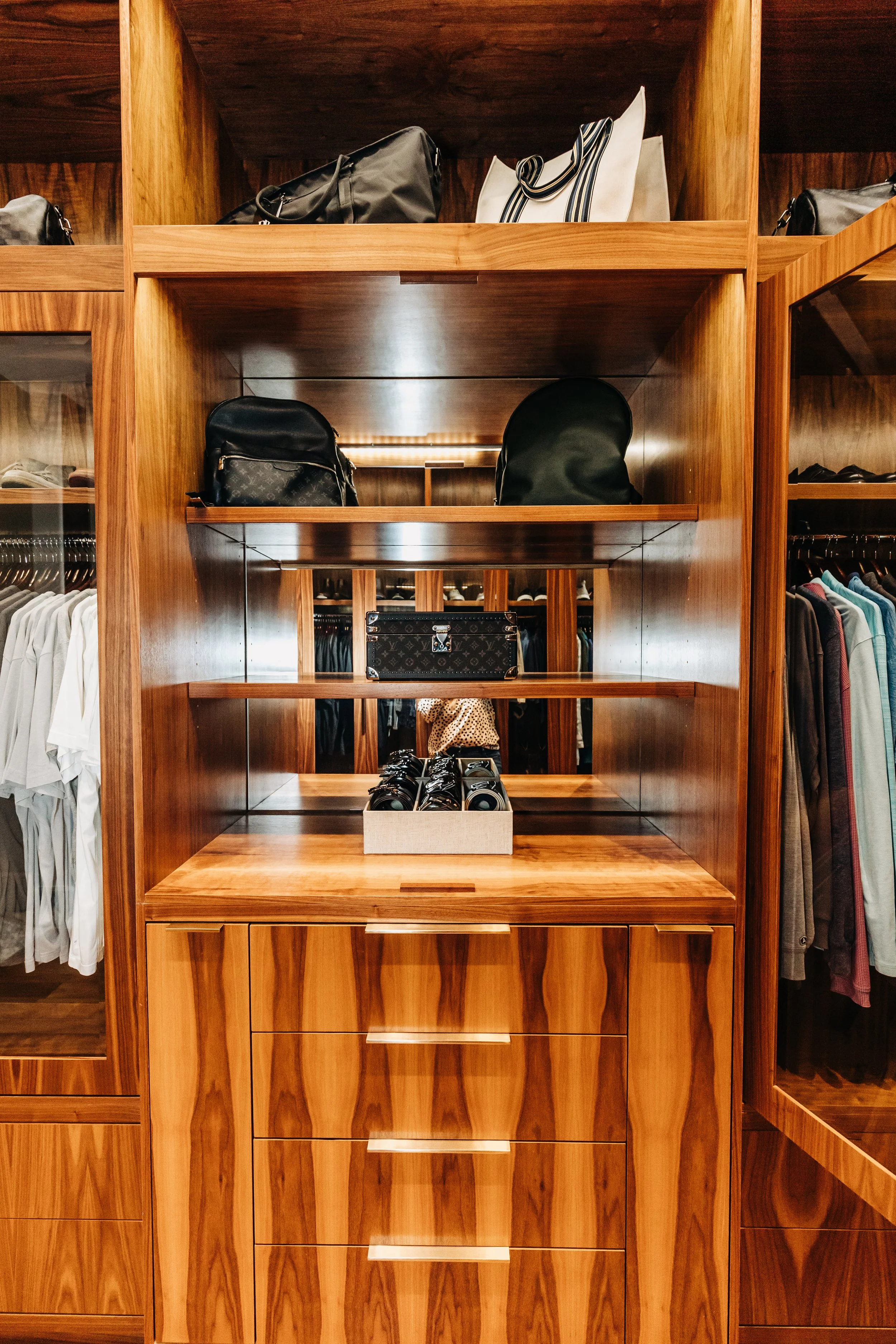 Wooden closet with shelves displaying handbags, shoes, and clothing.