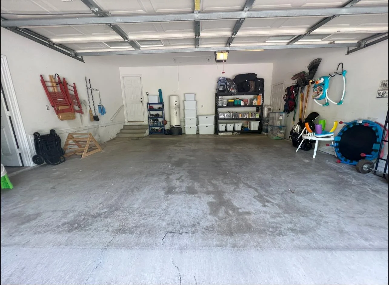 Empty garage with organized storage shelves, exercise equipment, and outdoor toys on the walls.
