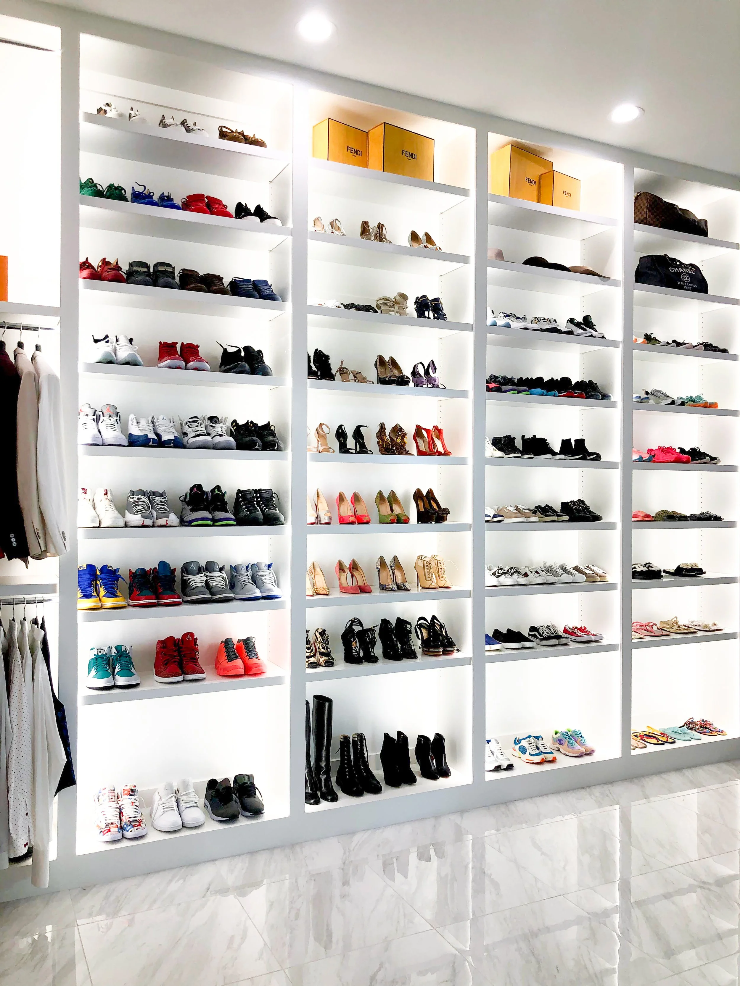 Display of various shoes and handbags on white shelves in a retail store.