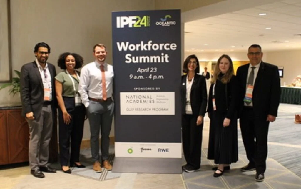A group of six diverse adults standing next to a sign at the Workforce Summit event, held on April 23 from 9 a.m. to 4 p.m., sponsored by National Academies and other organizations.