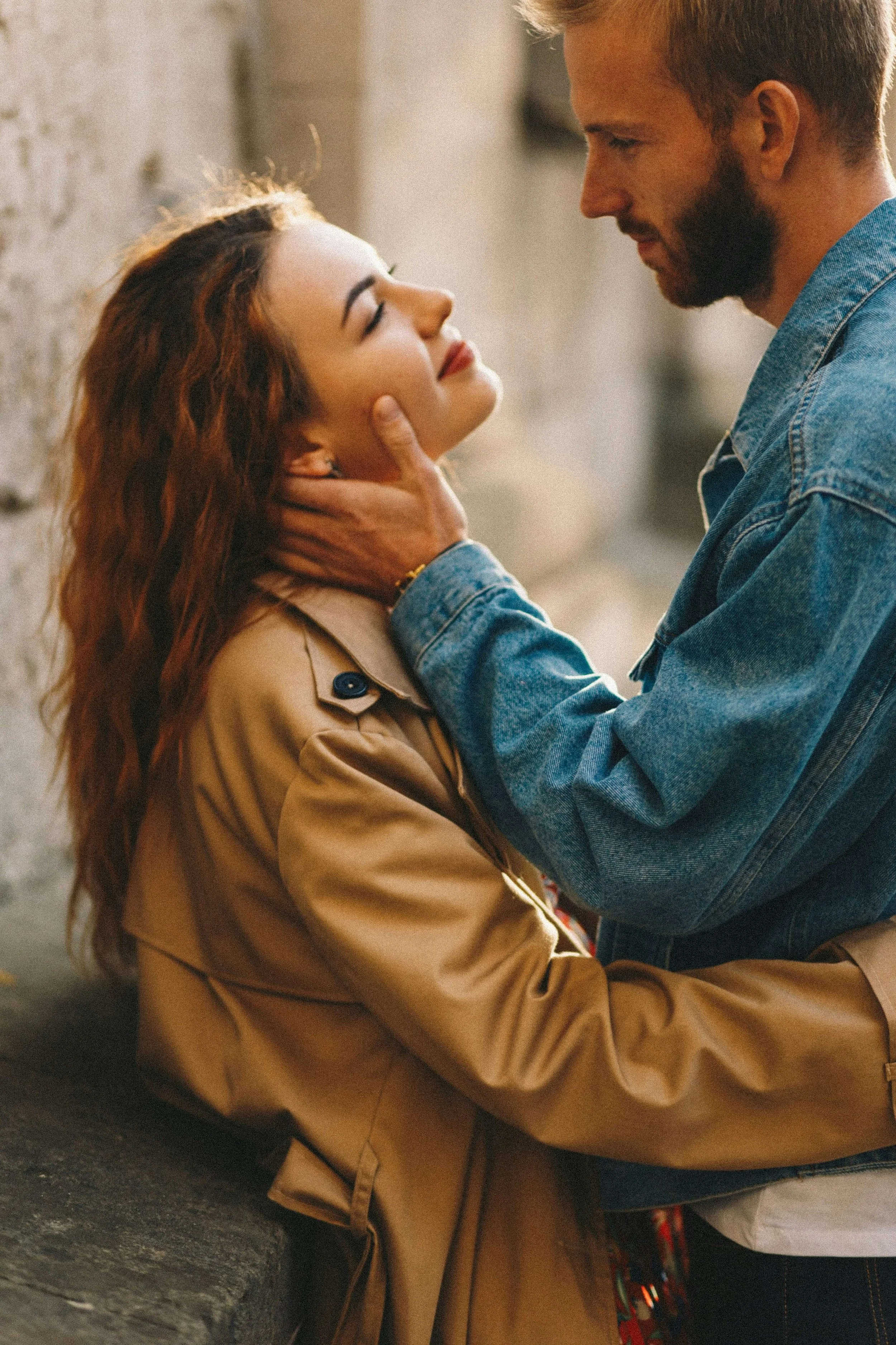Couple standing close with a tender hand to the face, representing repair and reconnection after conflict in couples therapy