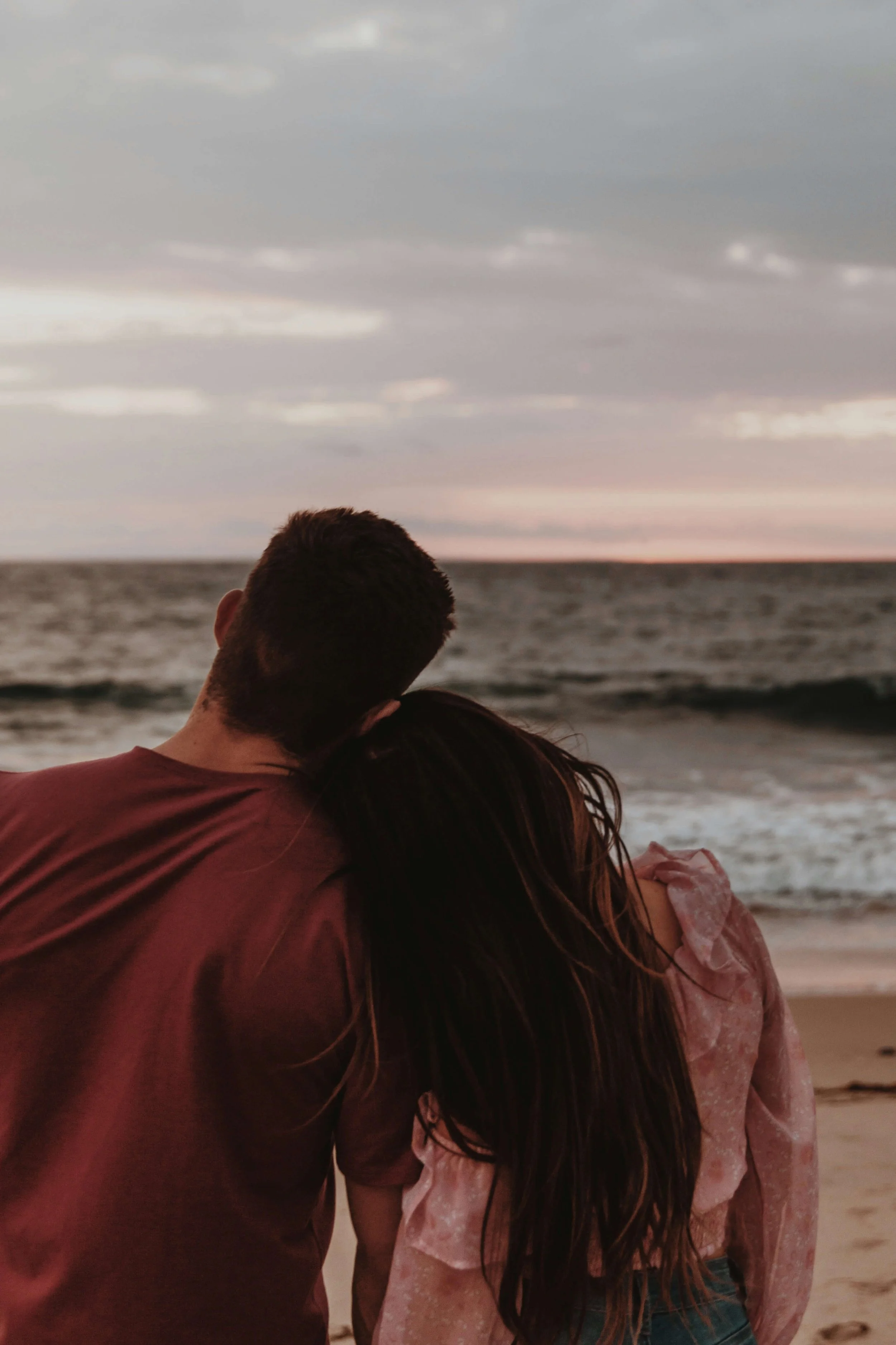 Couple embracing at the beach at sunset, representing clarity and connection after discernment therapy in Needham, MA