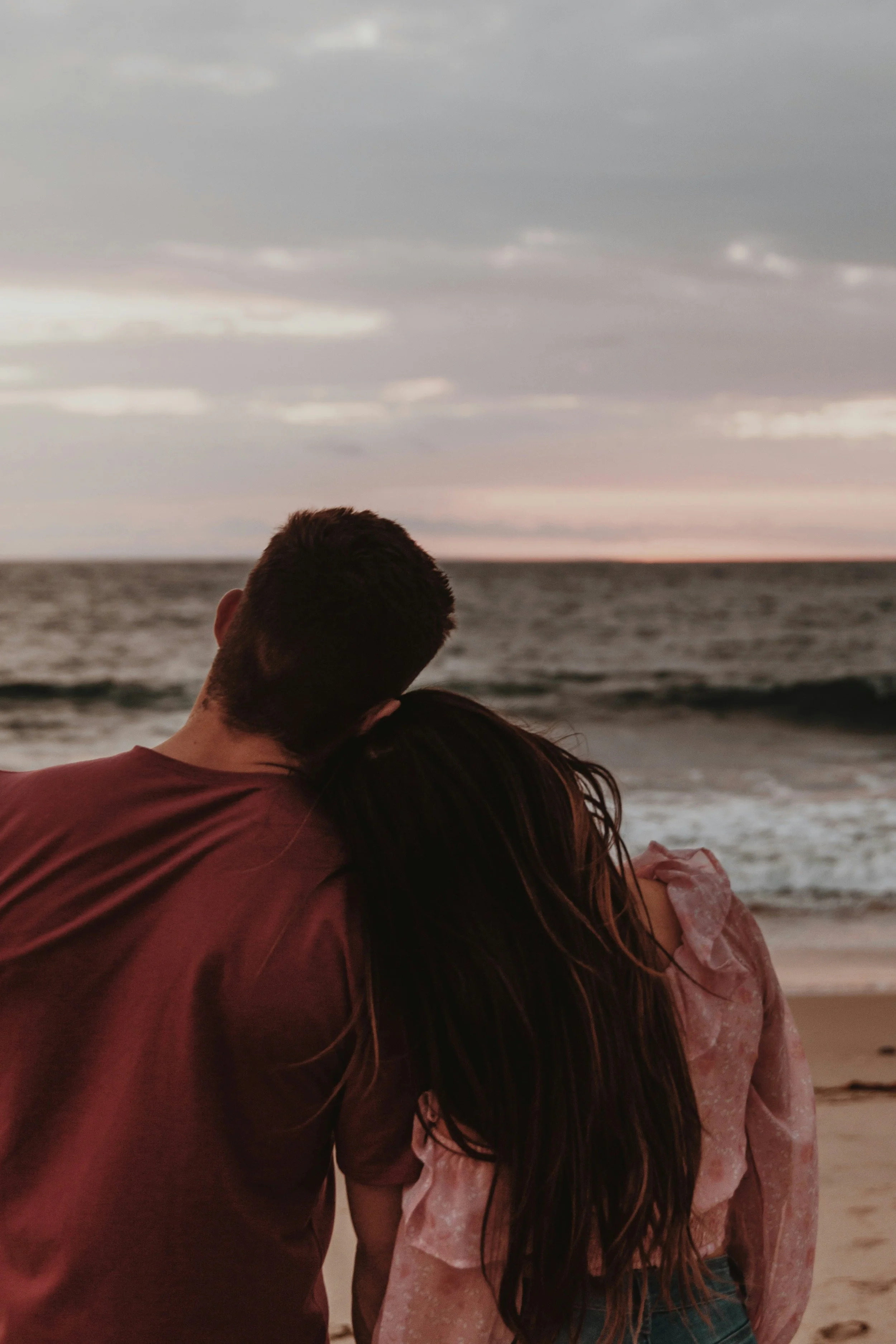 Couple embracing at the beach at sunset, representing clarity and connection after discernment therapy in Needham, MA