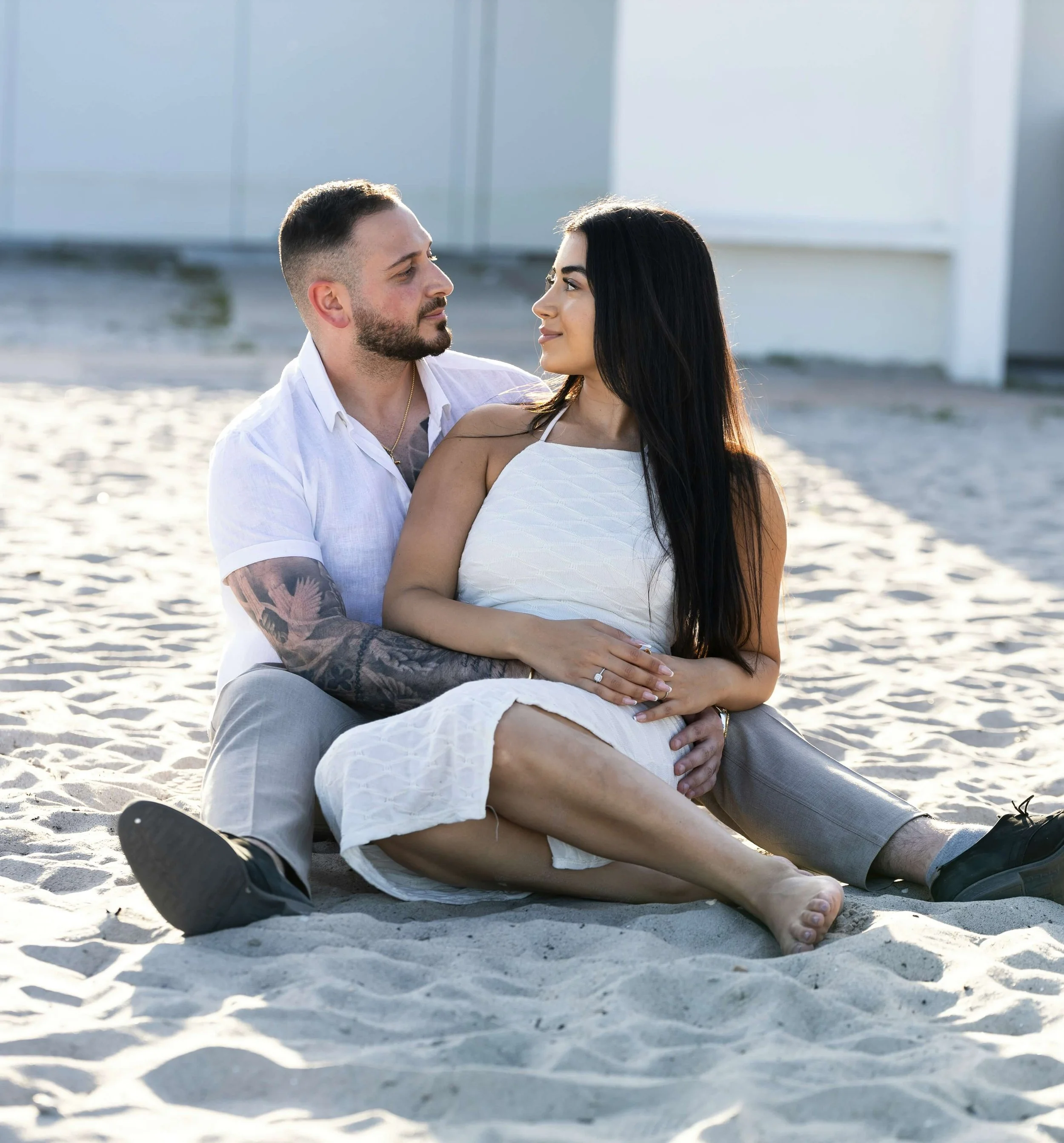 Couple sitting close together on the beach looking at each other, representing renewed desire and intimacy in couples therapy.