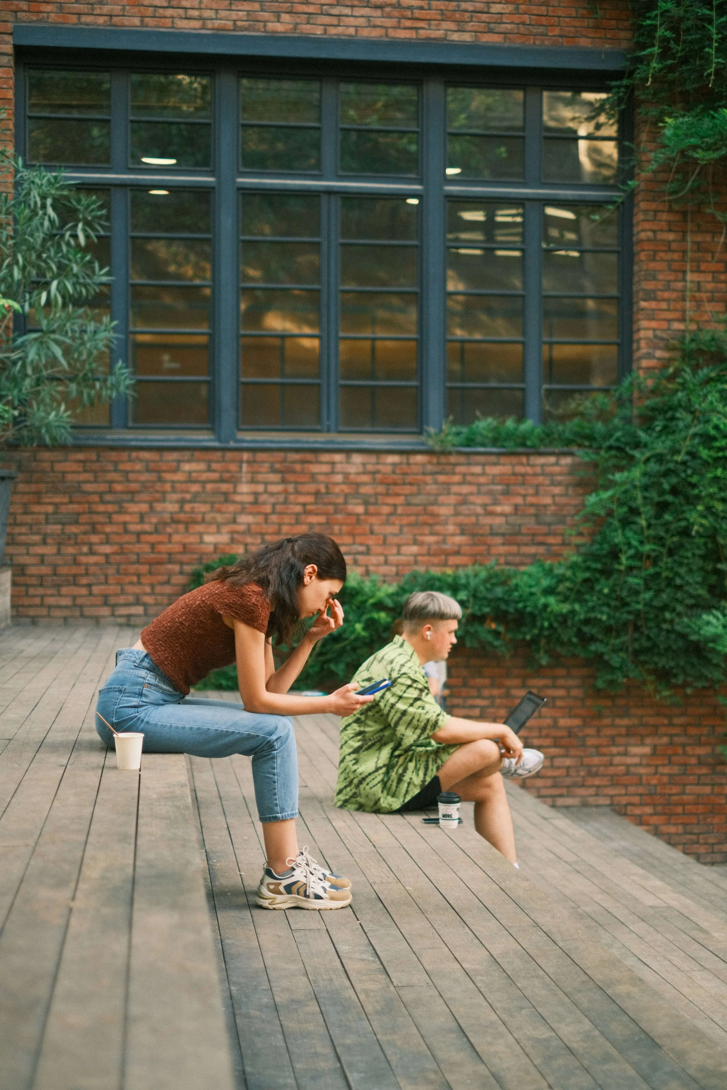 Couple sitting apart absorbed in their phones and laptop, representing emotional distance couples let build before seeking therapy in Needham, MA