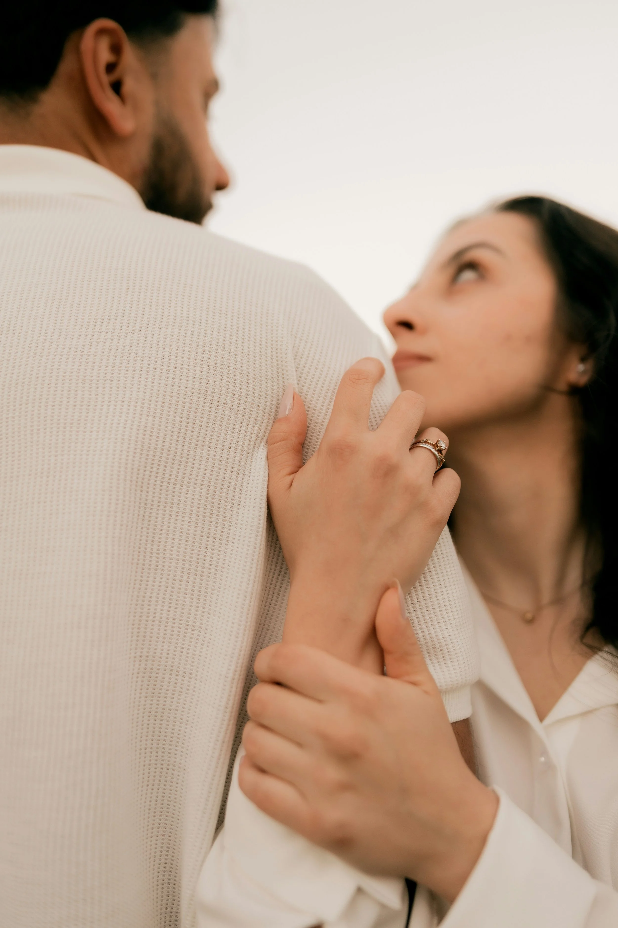 Woman looking up at her partner while holding his arm, a moment of tentative reconnection in affair recovery therapy, Needham, MA