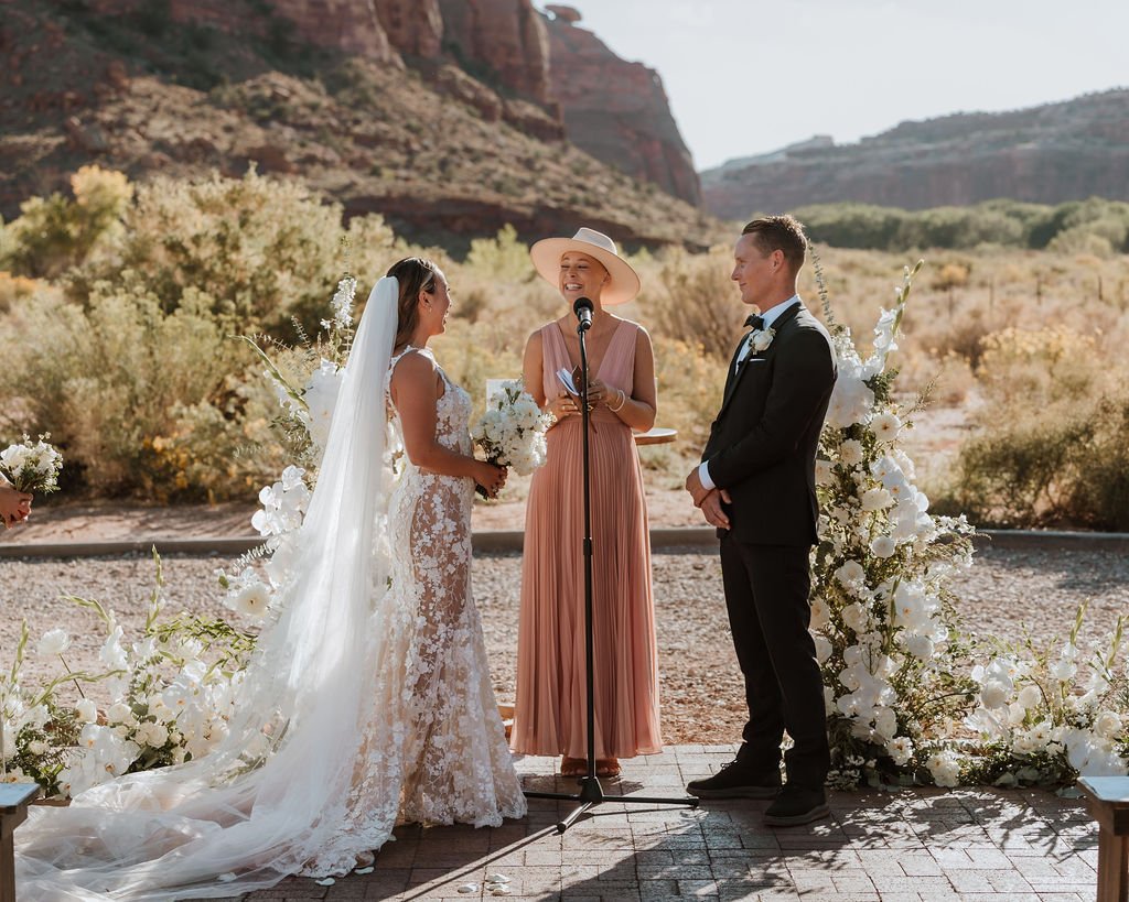 Bride and Groom stand at the altar featuring beautiful white flower towers arranged in a floral nest around them at the Red Earth Venue in Moab Utah
