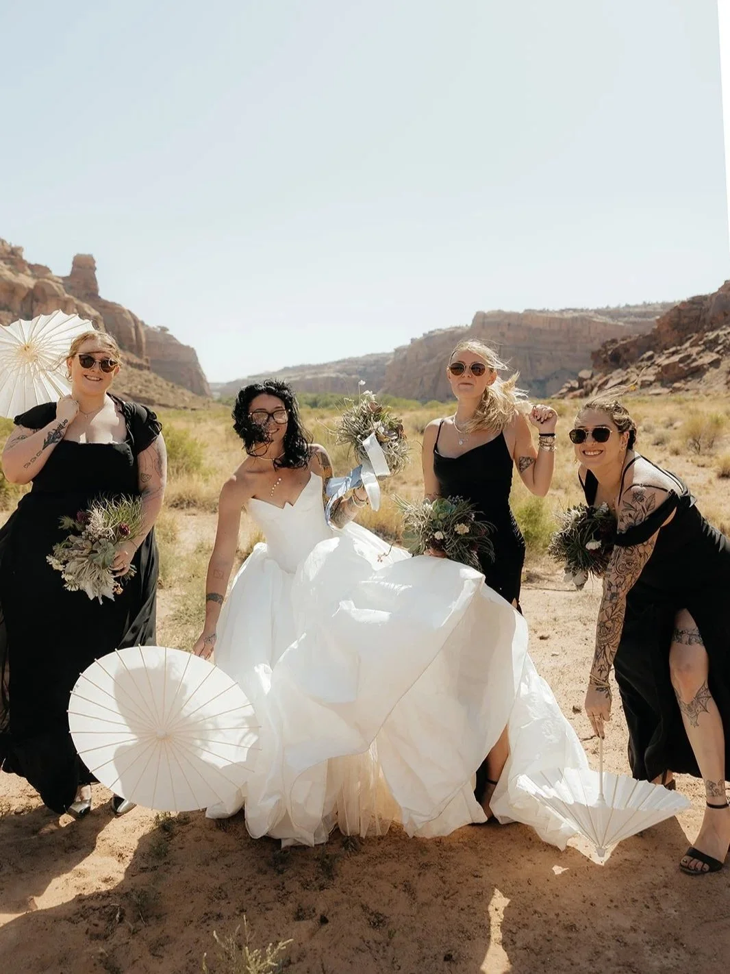 Bride and her bridal party holding parasols for a Moab wedding in the summertime at the Red Earth Venue.