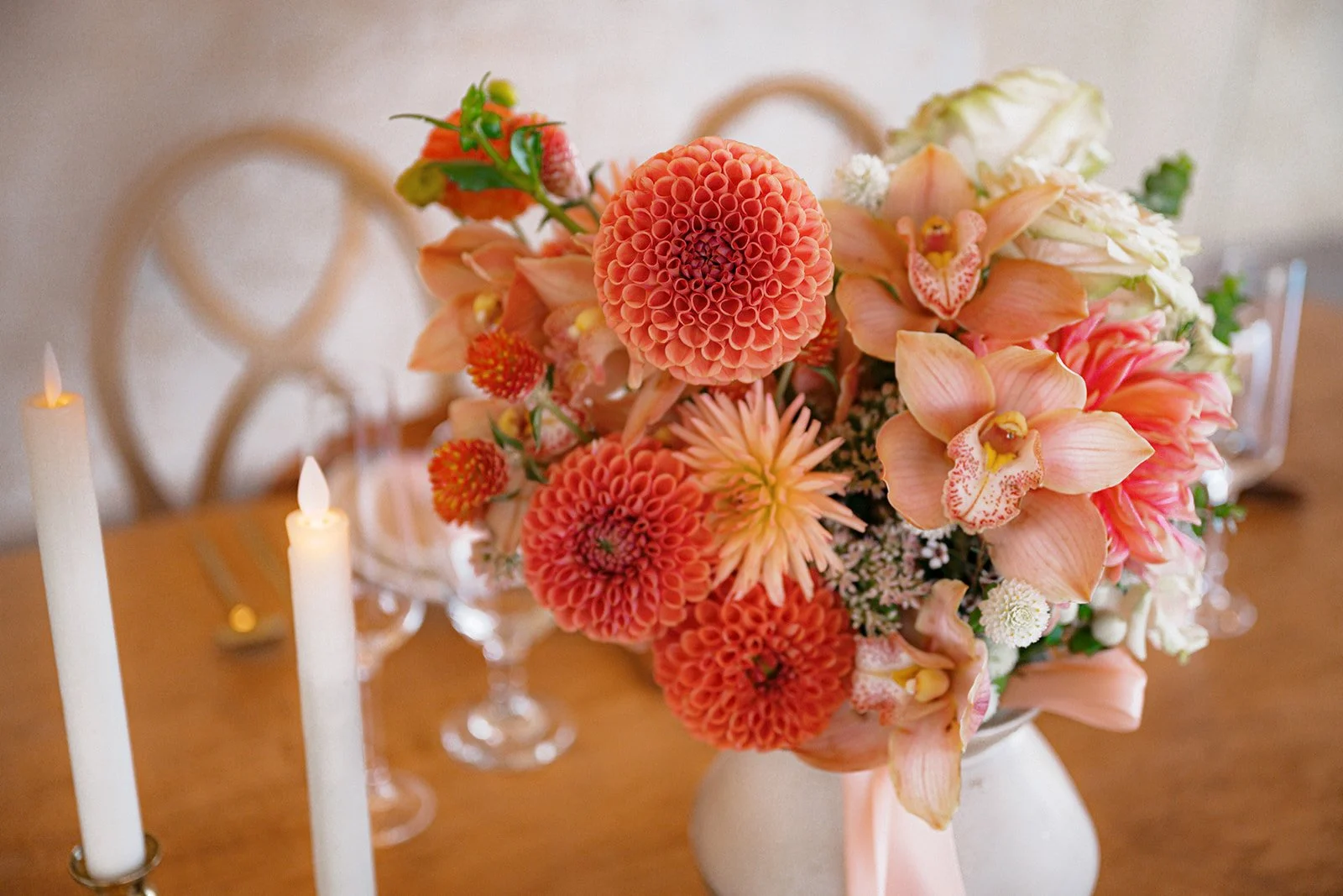 A bright bouquet featuring dahlias and orchids sits on a sweetheart table in a white vase at The Red Earth Venue in Moab Utah