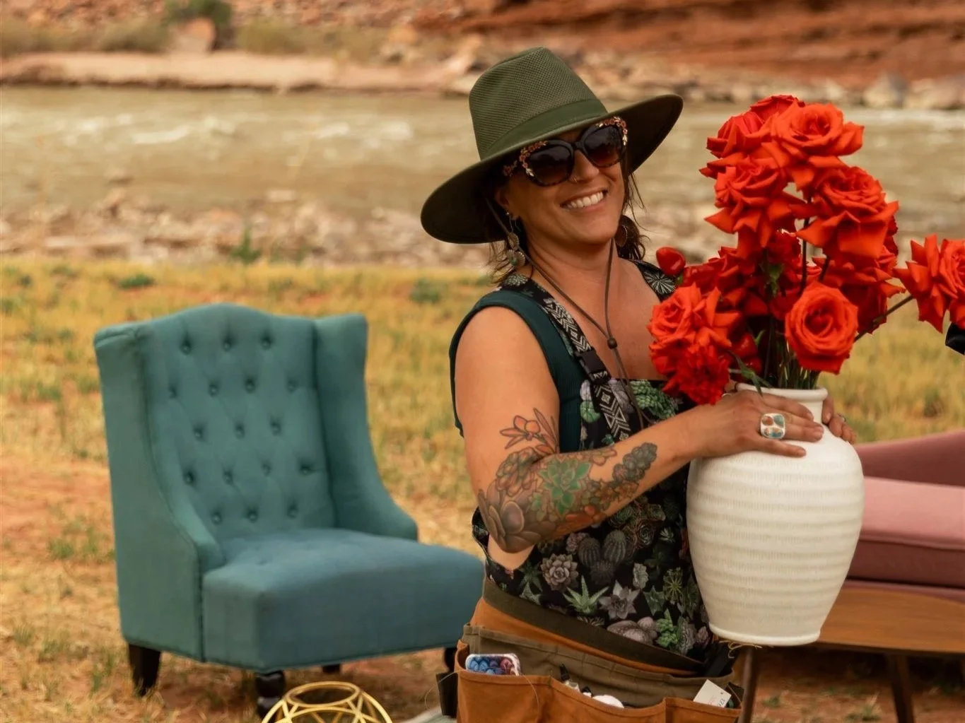 Moab wedding florist Tangled Sage carries a large vase of red roses to the next location