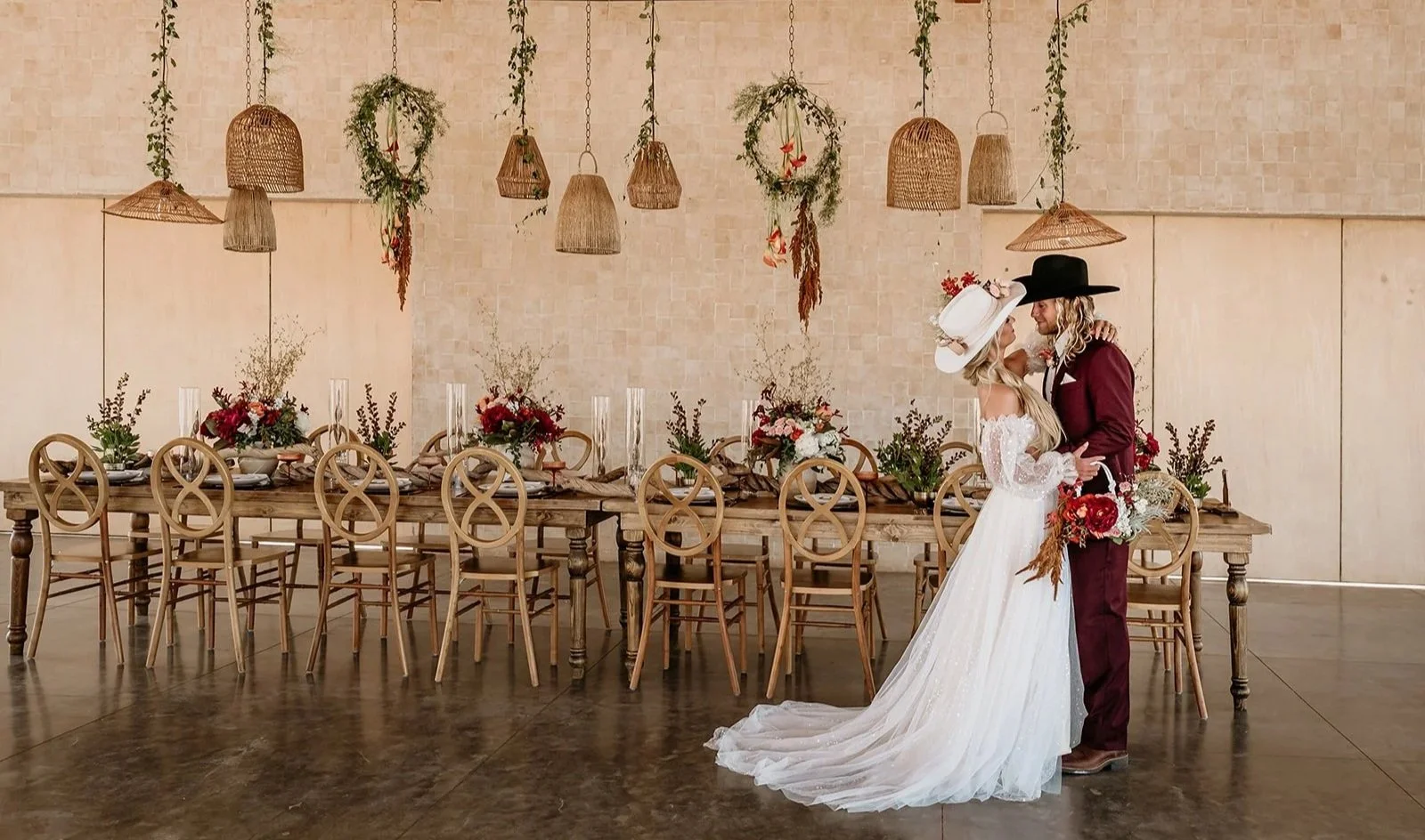 western wedding couple embraces in front of their wedding table featuring floral designs and hanging lanterns at the Red Earth Venue