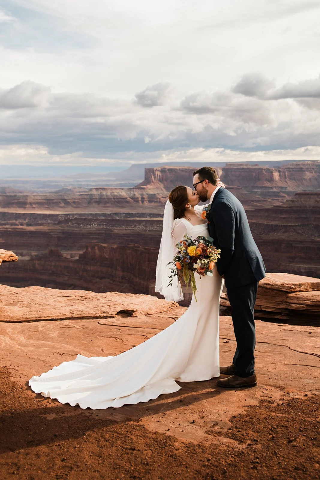 bride and groom kissing at a beautiful desert vista in Moab, UT
