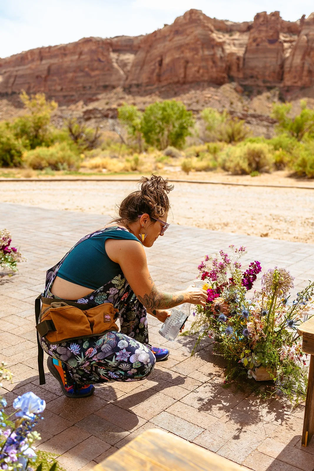 Moab florist sprays water on the ceremony florals for an outdoor wedding at The Red Earth Venue.