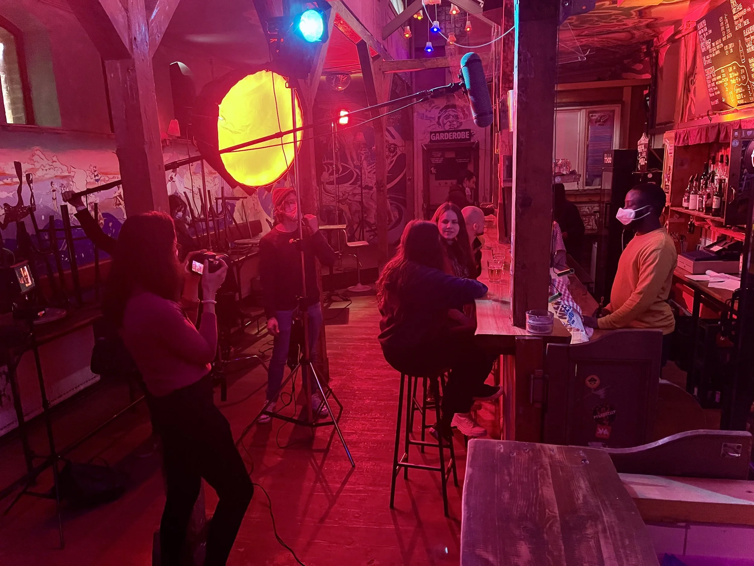 Troupe che gira in un bar illuminato di rosso intenso con un pallone luminoso giallo