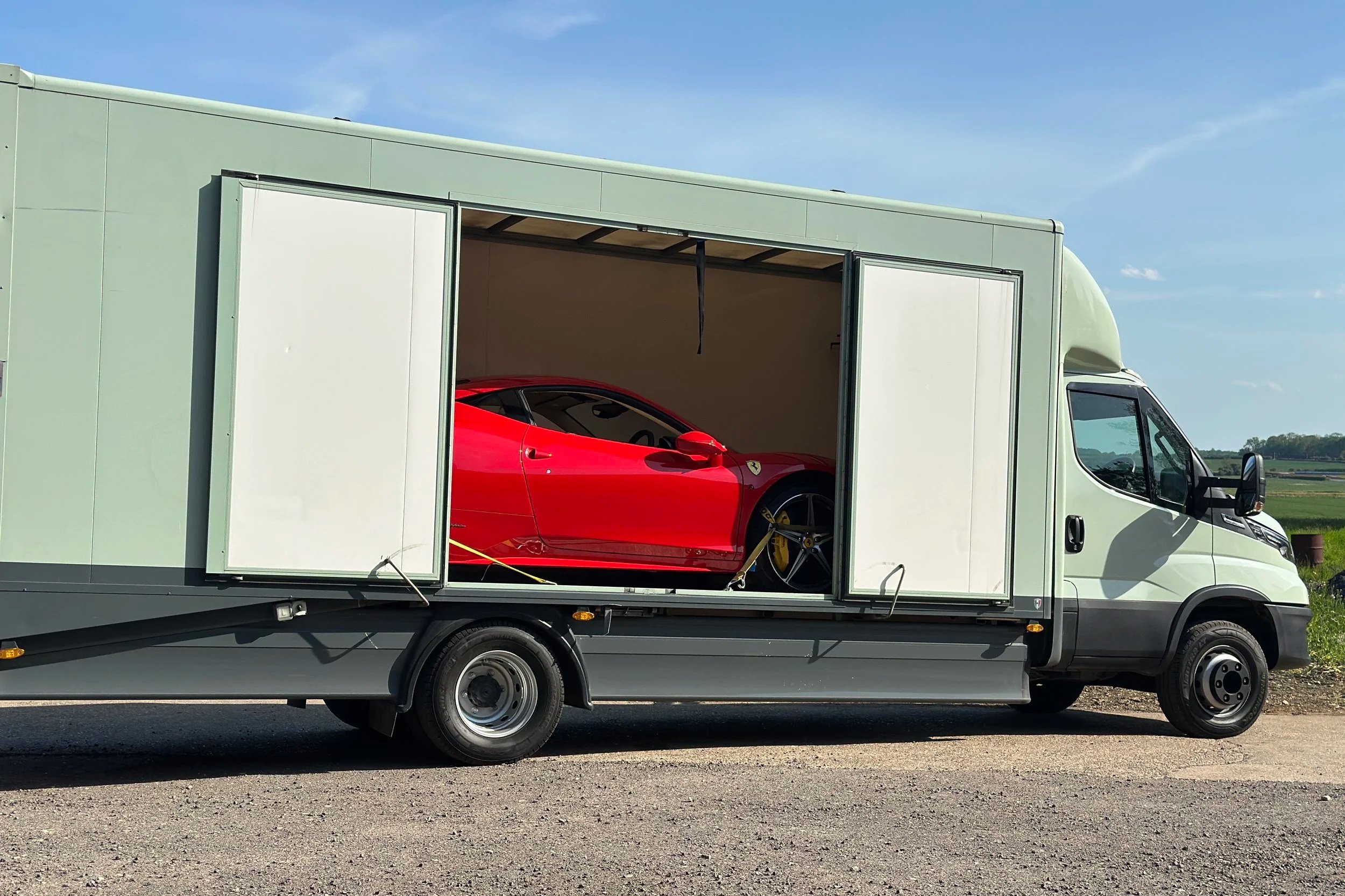 enclosed car transport HGV with the doors open showing a red Ferrari inside