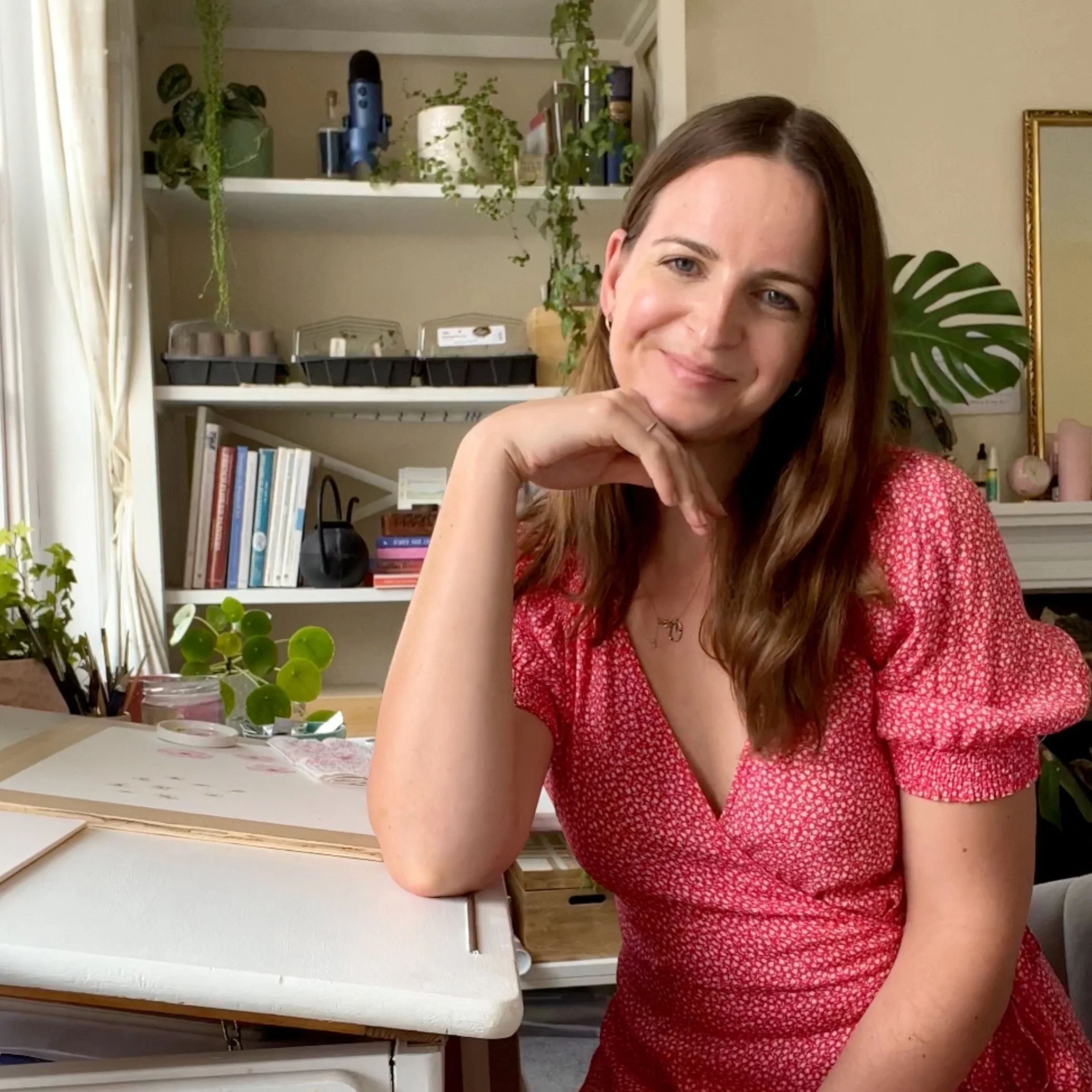 Botanical artists Helen Cousins sitting at her desk in her studio.