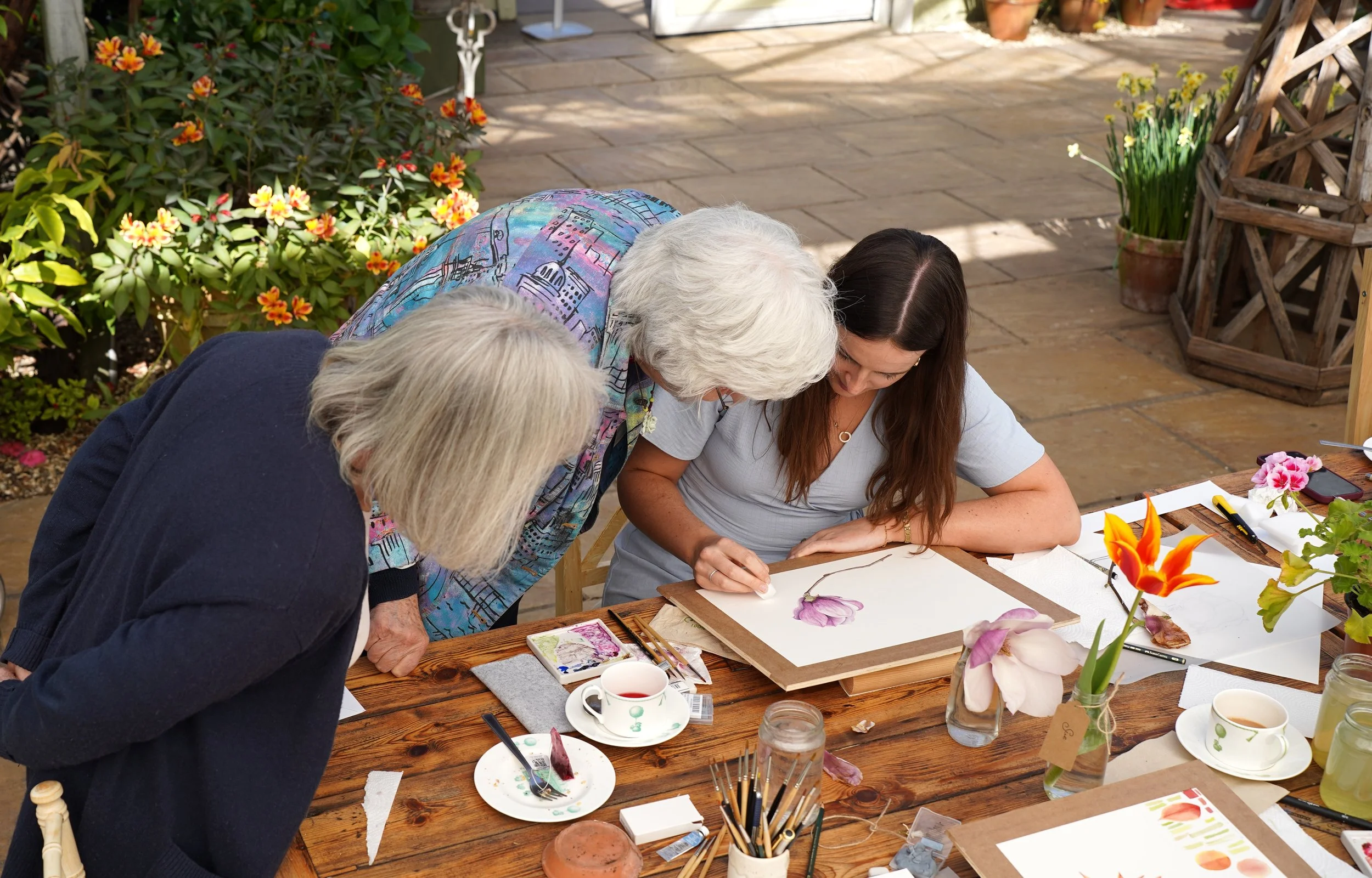 Helen Cousins guiding a student painting a flower during an in-person botanical art workshop in England