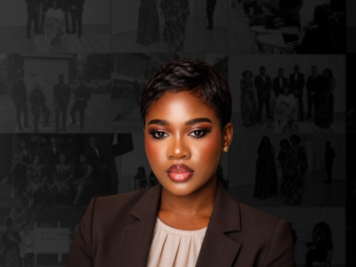 Portrait of a confident young Black woman with short hair, wearing a dark blazer and beige blouse, standing against a dark background with collage of black and white photographs.