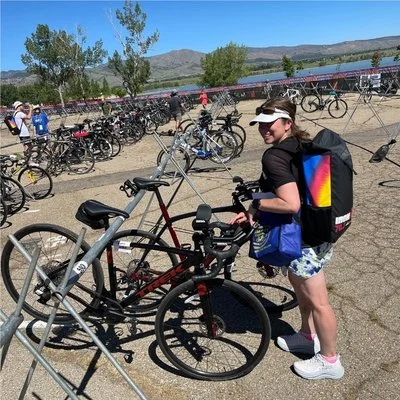 Athlete checking her bike in transition before Ironman 70.3, surrounded by rows of racked bicycles before race day.