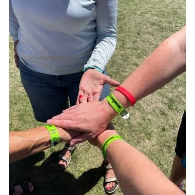 Four hands stacked together before Ironman 70.3 Boulder race day, symbolizing support between three first-time athletes and one experience Ironman.
