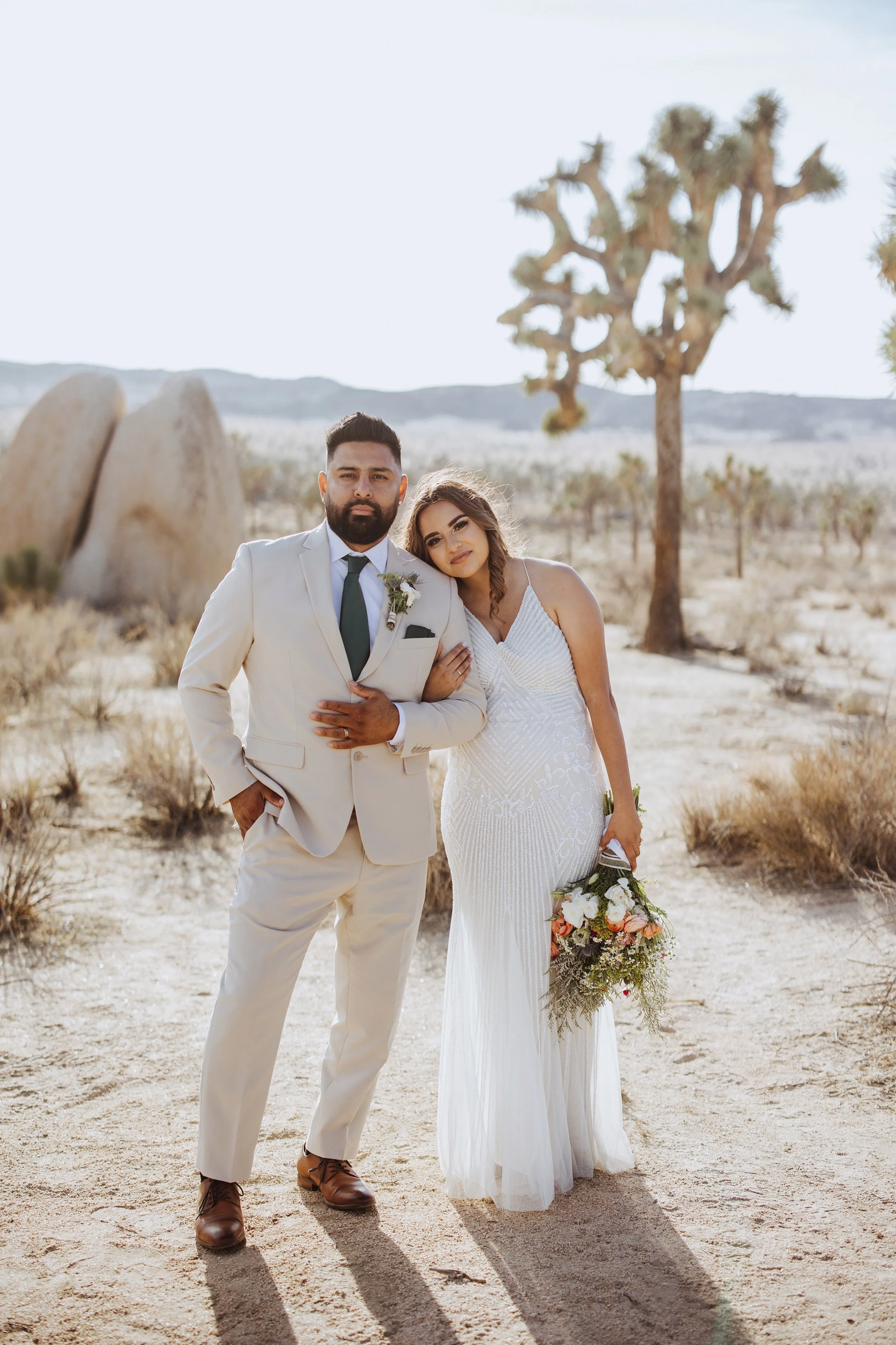 Laurie’s customers, Mariana and Carmen holding hands on a green lawn on their wedding day.