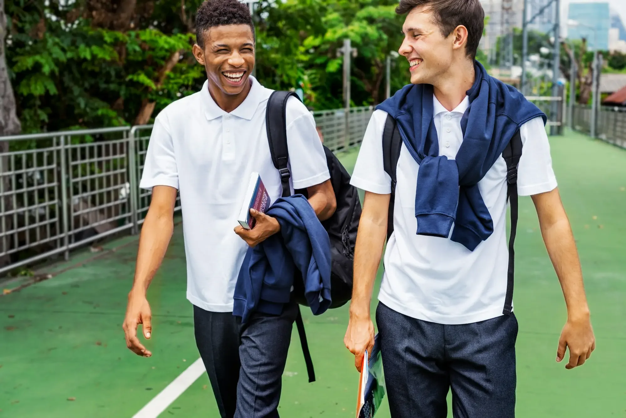 Two men smiling and laughing wearing white polo shirts with greenery in the background in a Seattle park.
