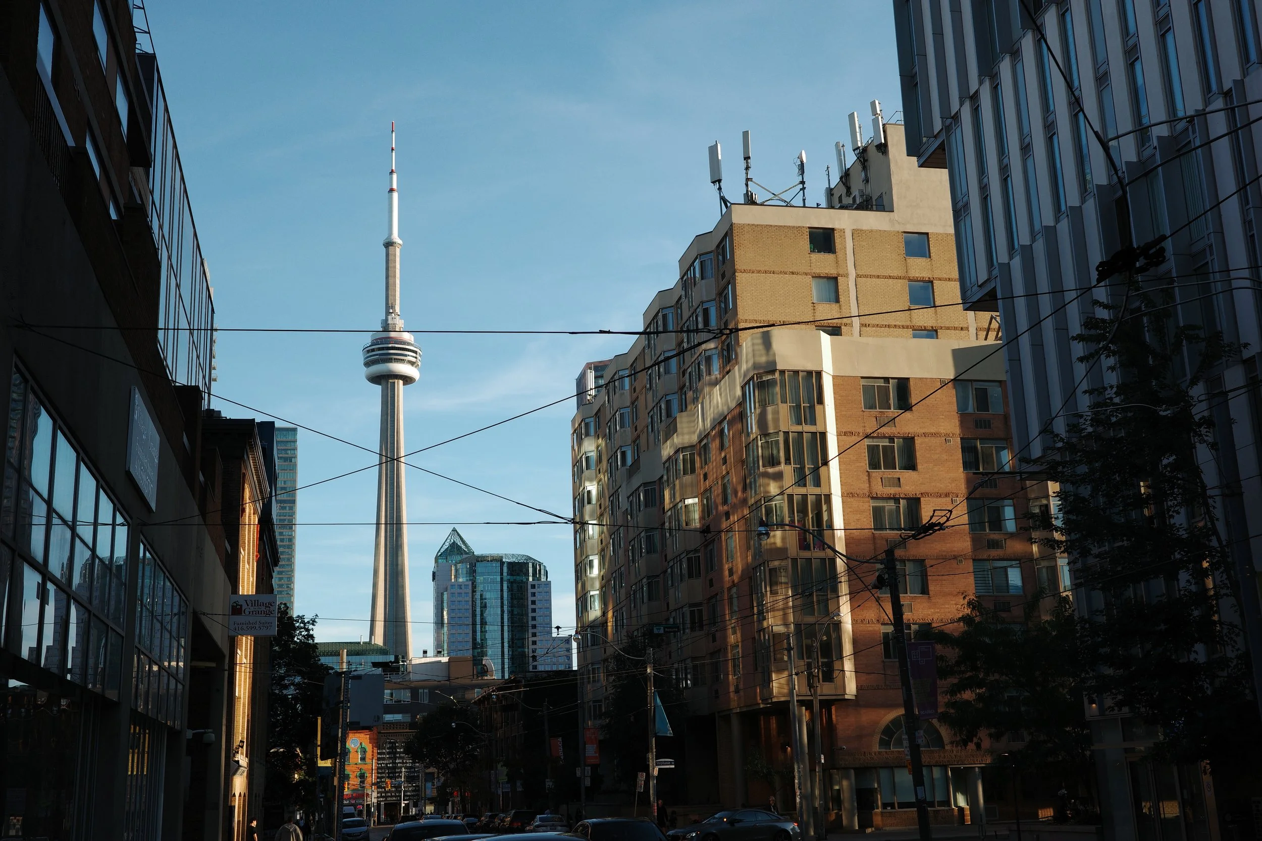View of downtown Toronto with the CN Tower in the background, city buildings in the foreground, and power lines crossing the scene.