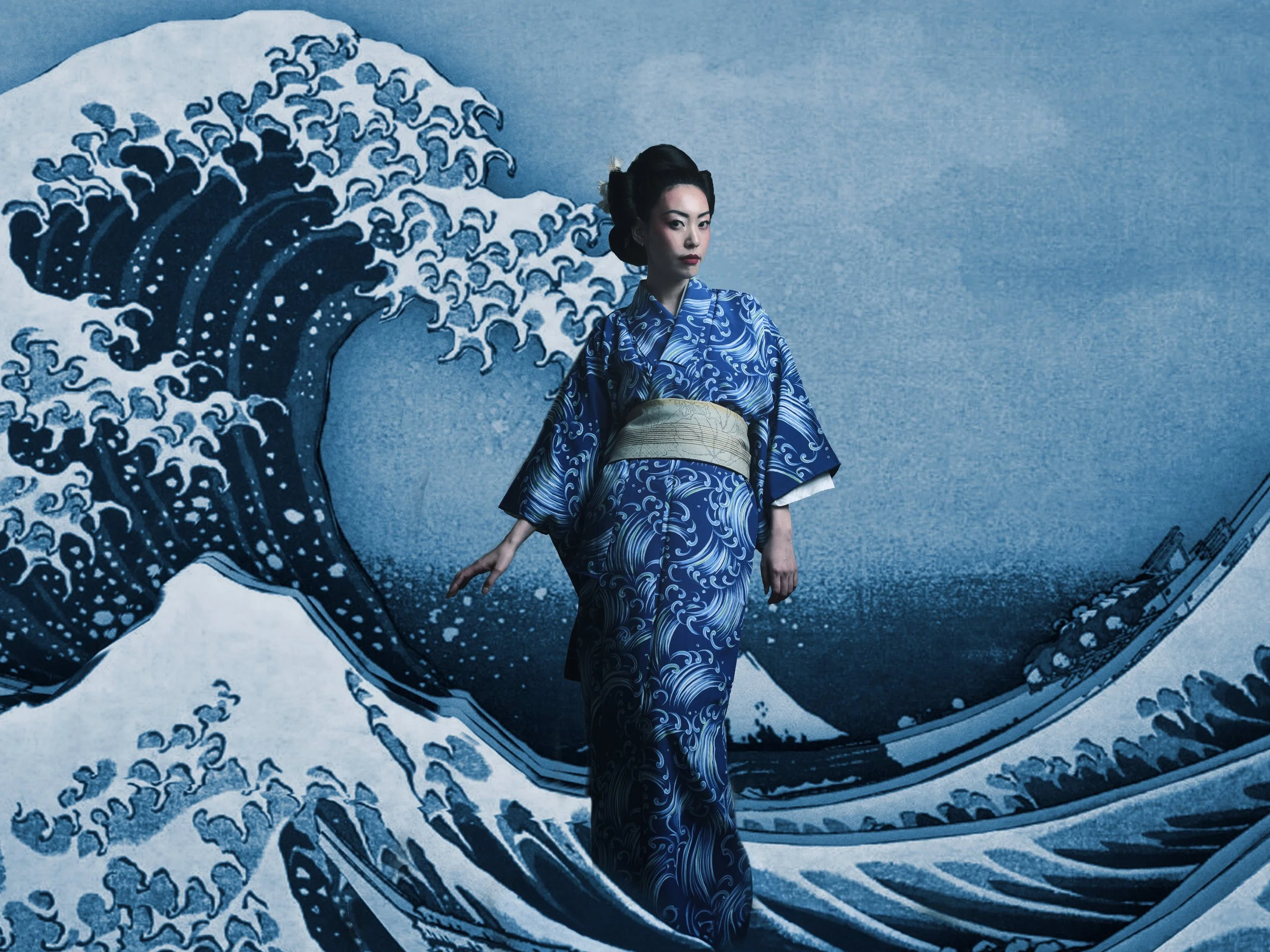 A woman in a traditional Japanese kimono standing in front of a mural of Tsunami waves.