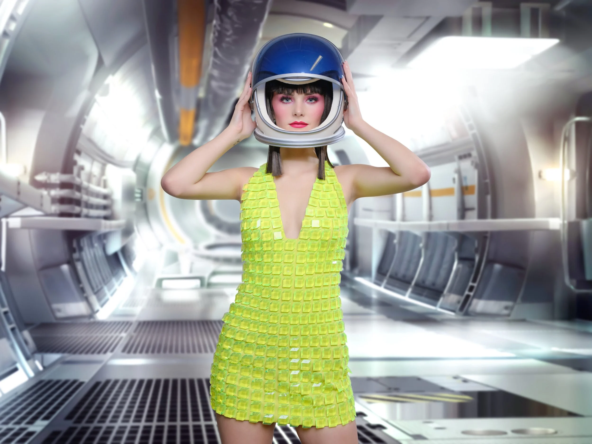 A woman in a yellow textured dress is in a futuristic space station or spaceship interior, holding a space helmet on her head, looking directly at the camera.