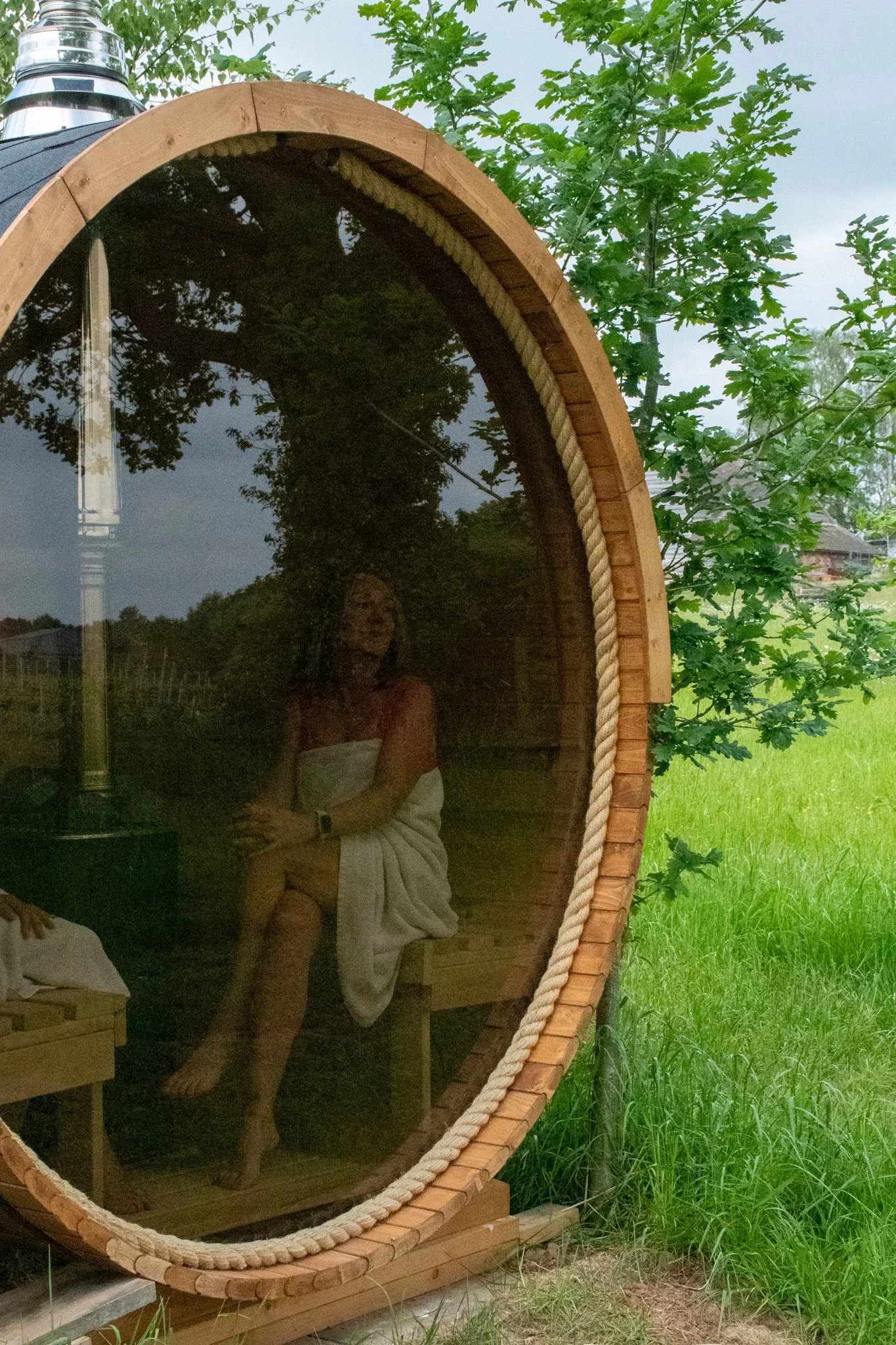 Guest relaxing in outdoor sauna overlooking lake and vineyard at Wagtail Retreat Worcestershire.