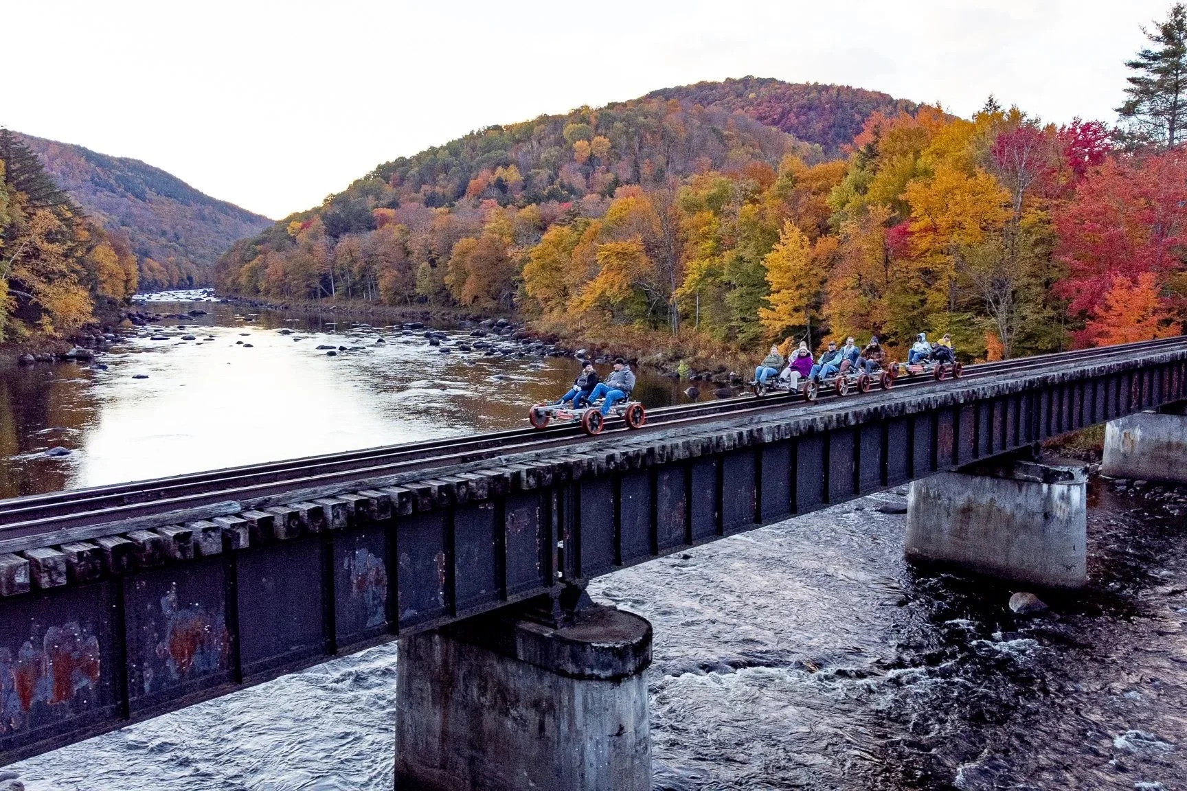 Rail bike ride in New York over a bridge with blue sky and green mountains in the background