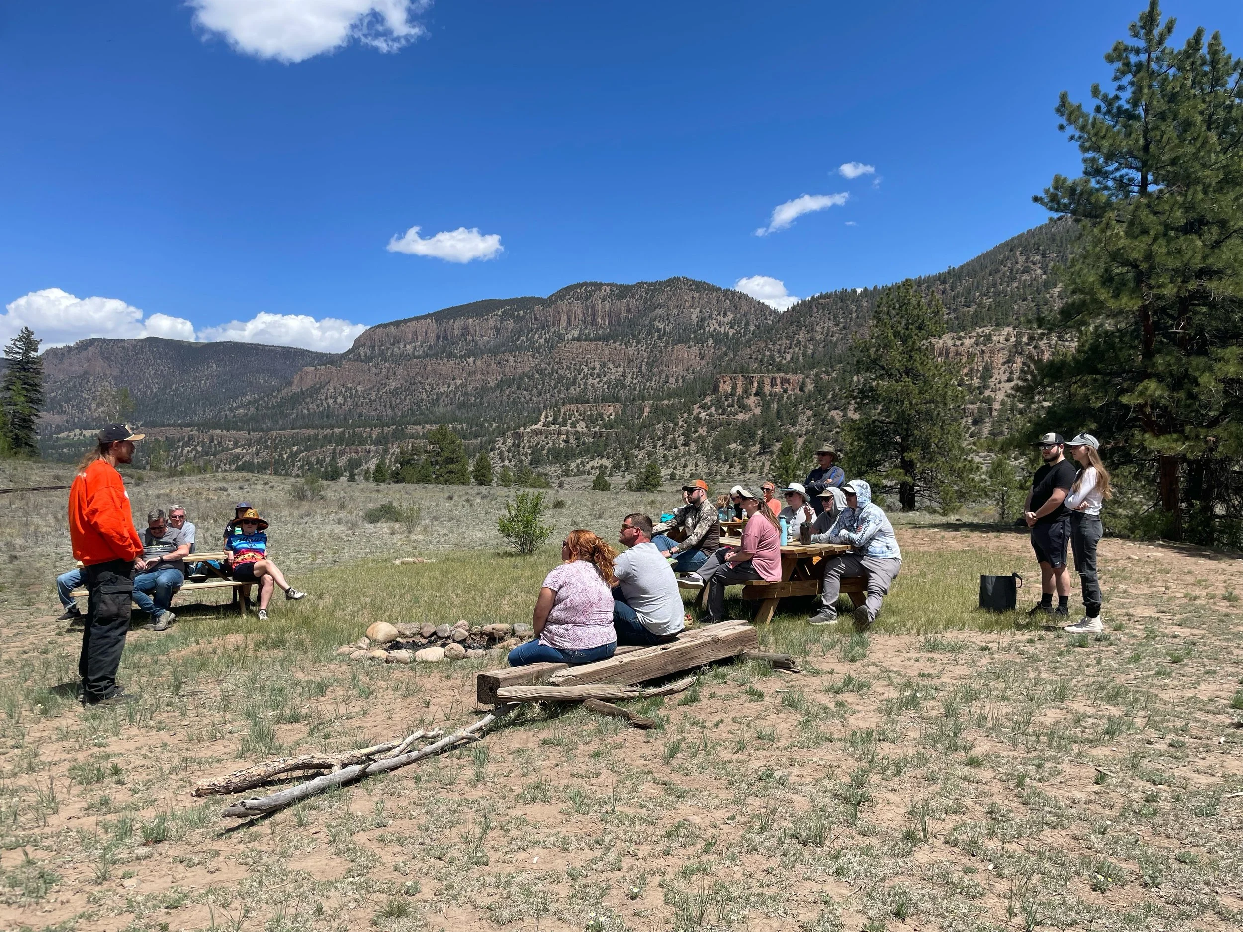 riders sit at picnic tables at the turnaround point while a Guide gives a history talk