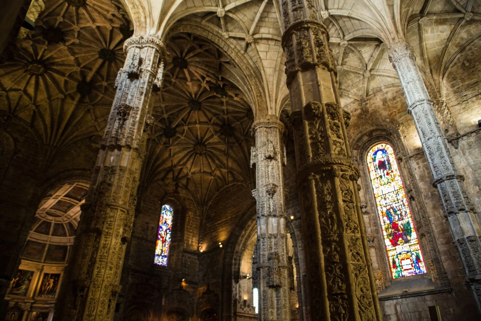 interior of the jeronimos monastery church with high stone vaulted ceilings and stained glass windows