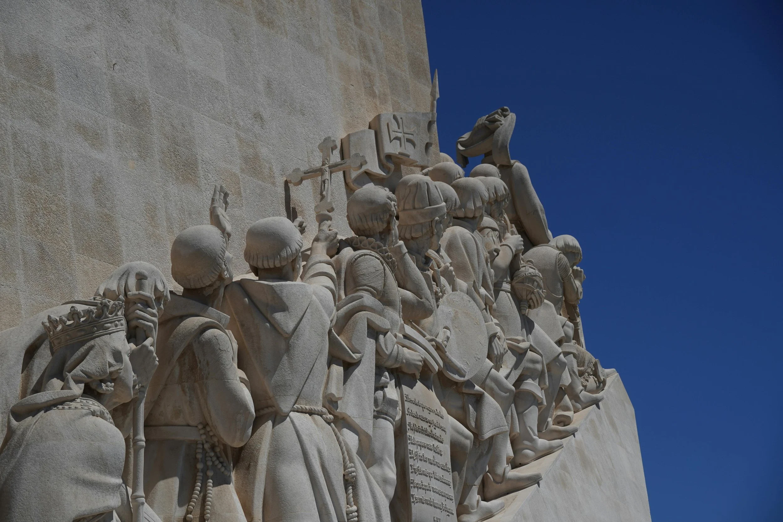 monument to the discoveries stone figures from behind