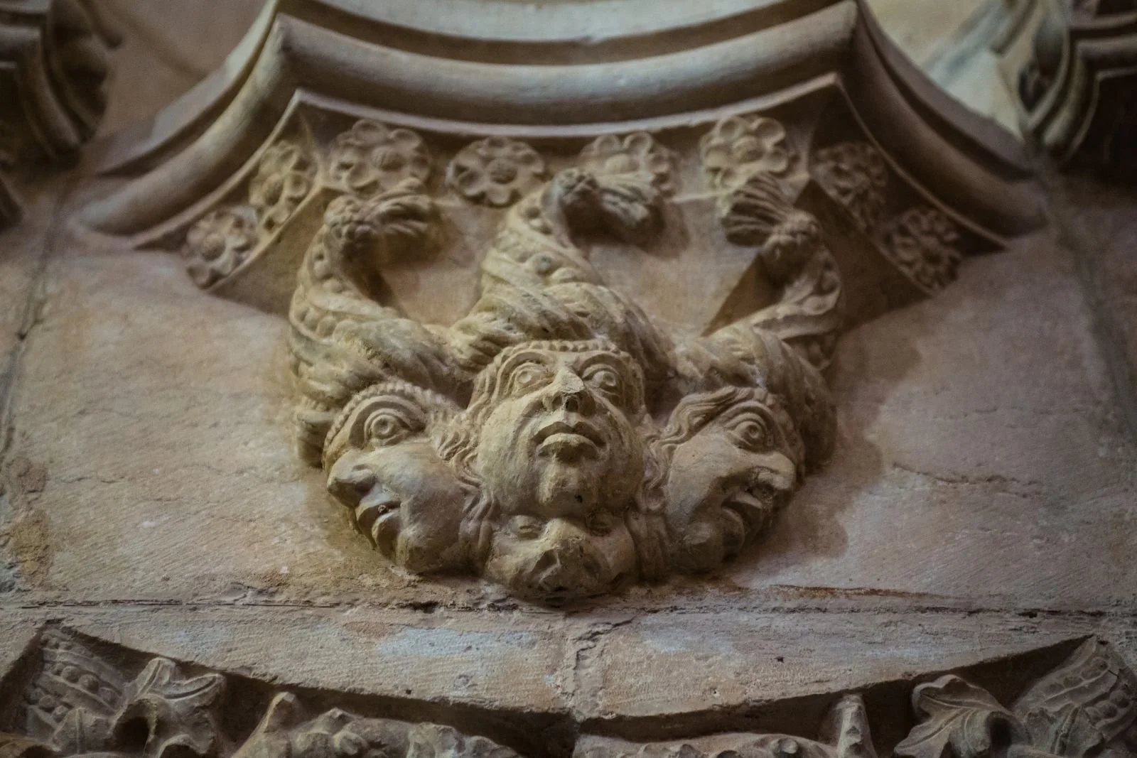 Carved stone detail of three faces in the jeronimos monastery