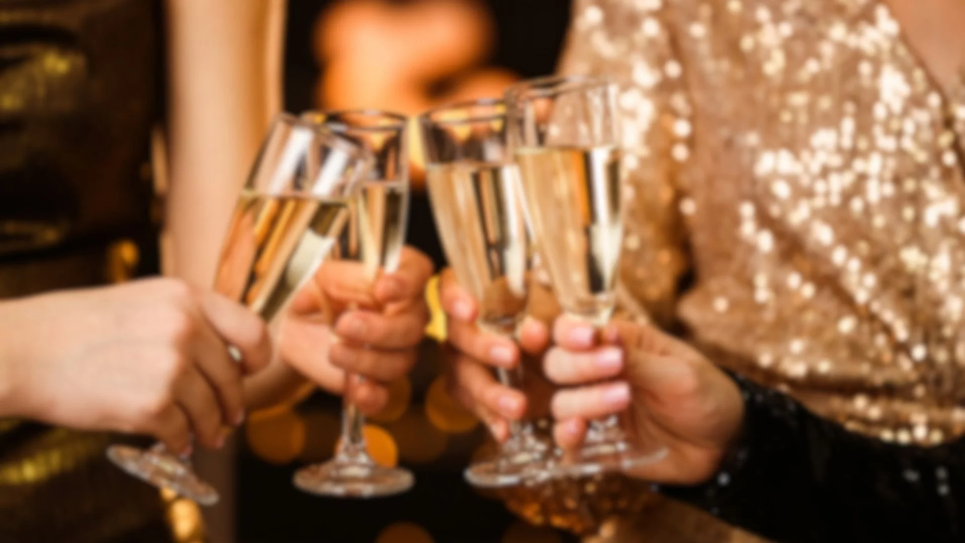 Multiple people holding champagne glasses in a toast, with a person in a gold sequined dress in the background.