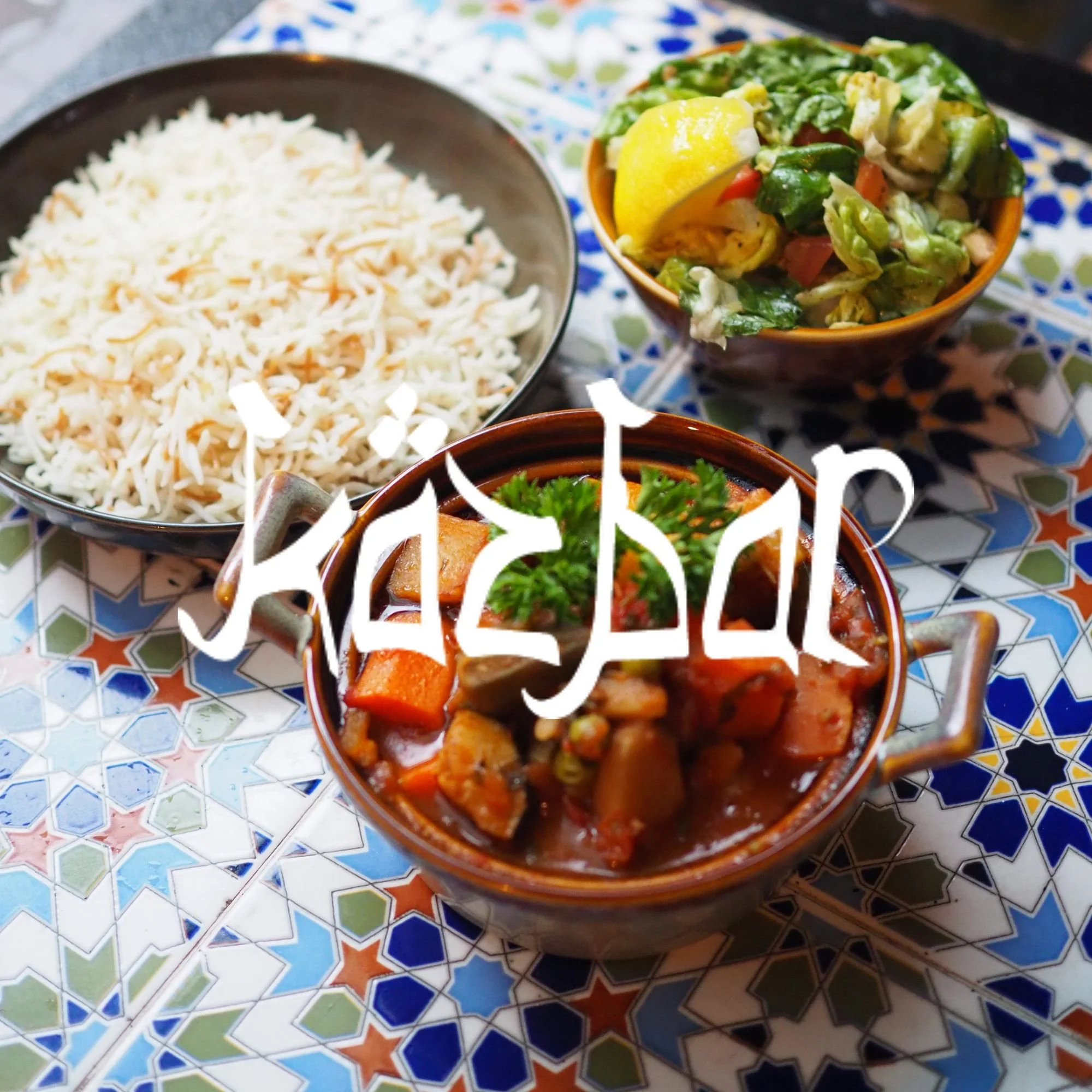 Colorful Moroccan-style ceramic table with bowls of Mexican food, including shredded cheese, chopped vegetables, and a steak dish garnished with fresh herbs.