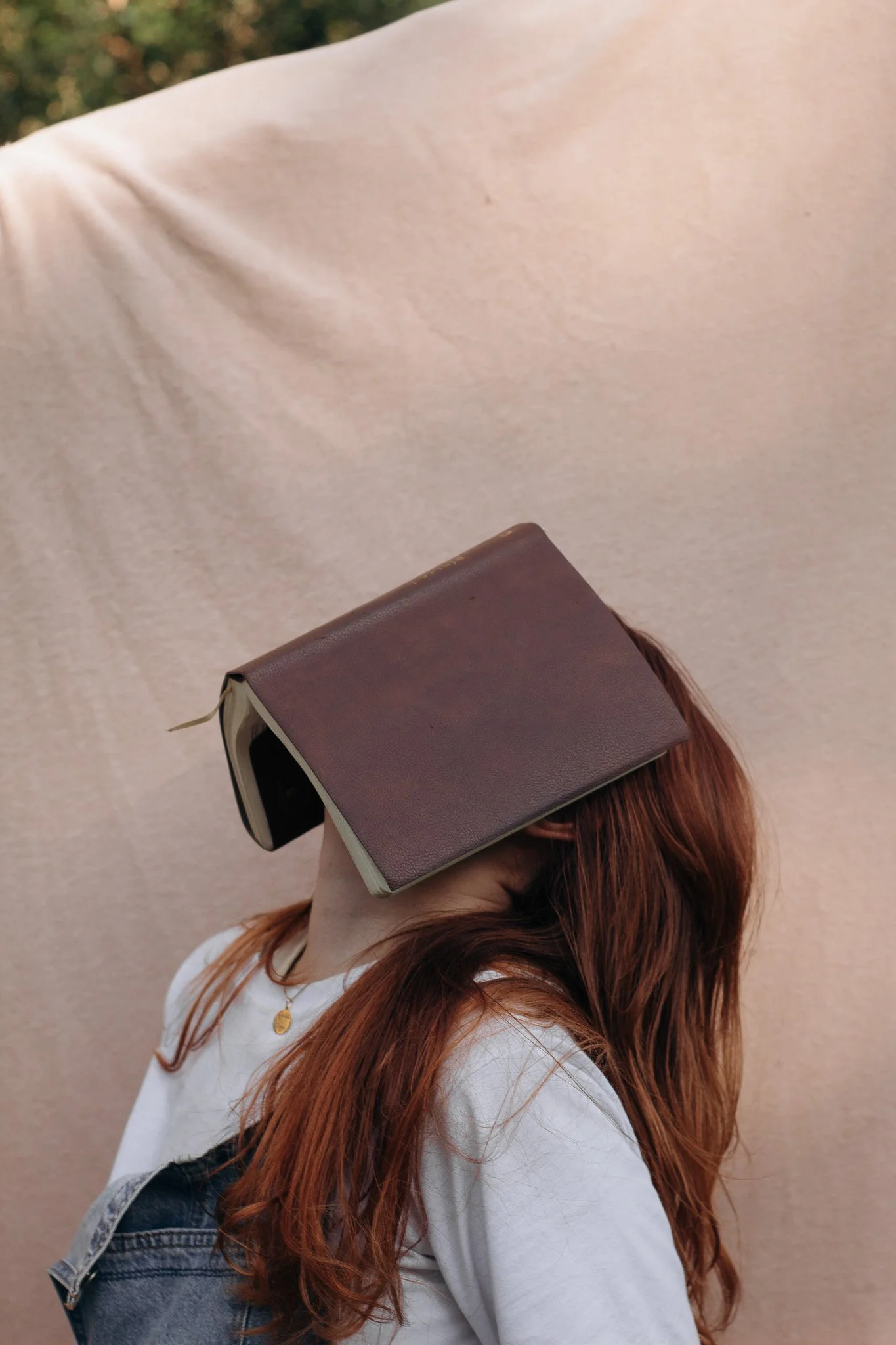 a girl has a book laying open on her face while her head is tilted toward the sky