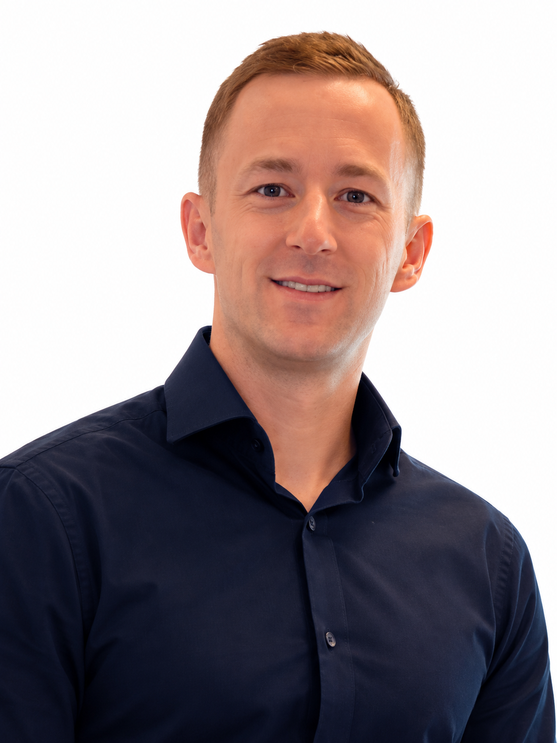 Headshot of a smiling man with short brown hair, wearing a dark blue collared shirt against a white background.