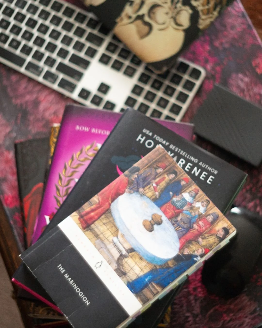 This is a stack of books with The Mabinogion on top, a keyboard is blurred out in the background.