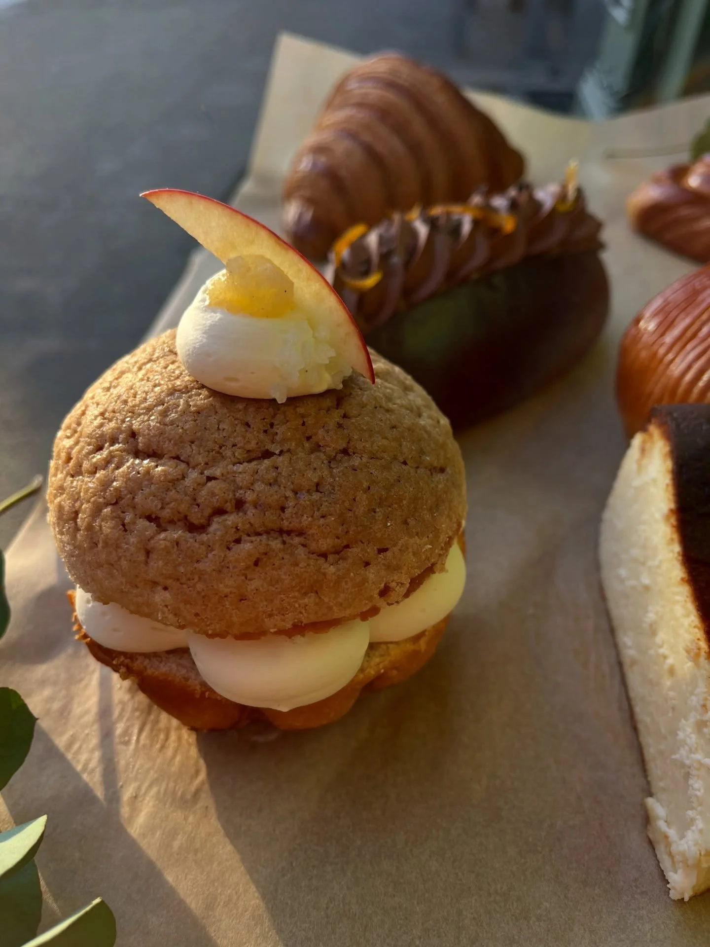 Spiced apple trop&eacute;zienne.

Pillowy soft brioche brushed with calvados syrup and filled with spiced apple compote and whipped calvados cream. Topped with a crunchy brown sugar craquelin. 

On the counter everyday for the rest of December 💚