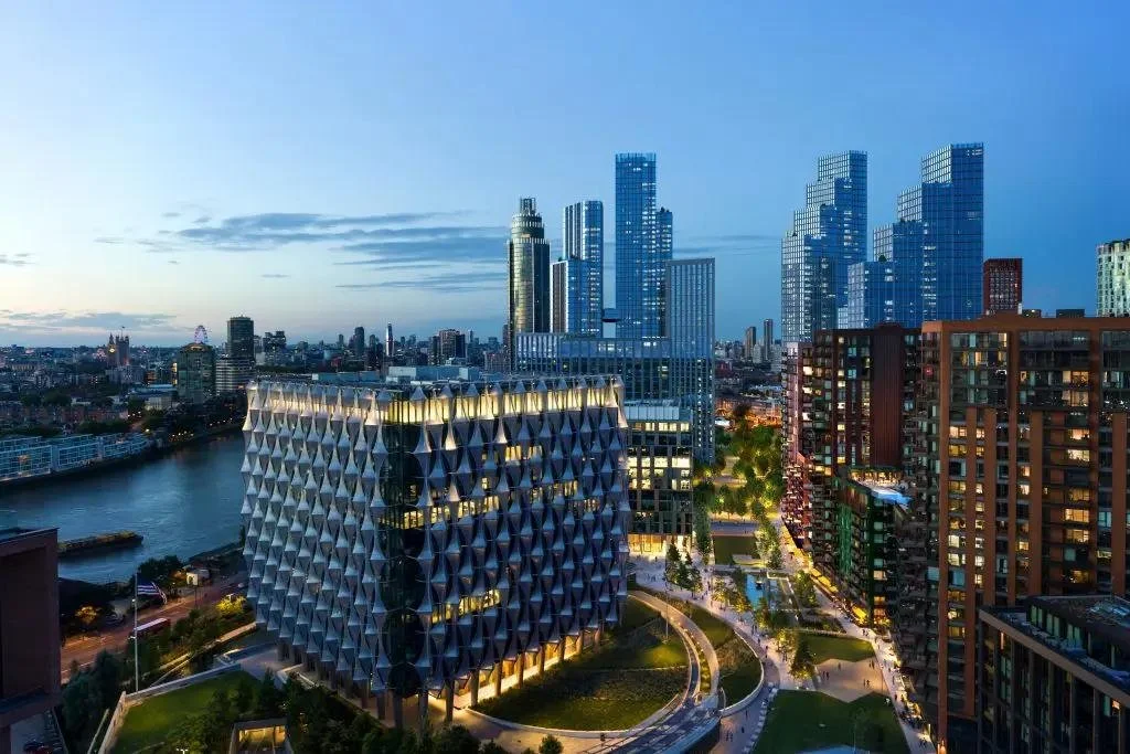 Cityscape at dusk featuring modern high-rise buildings and a river with a bridge.