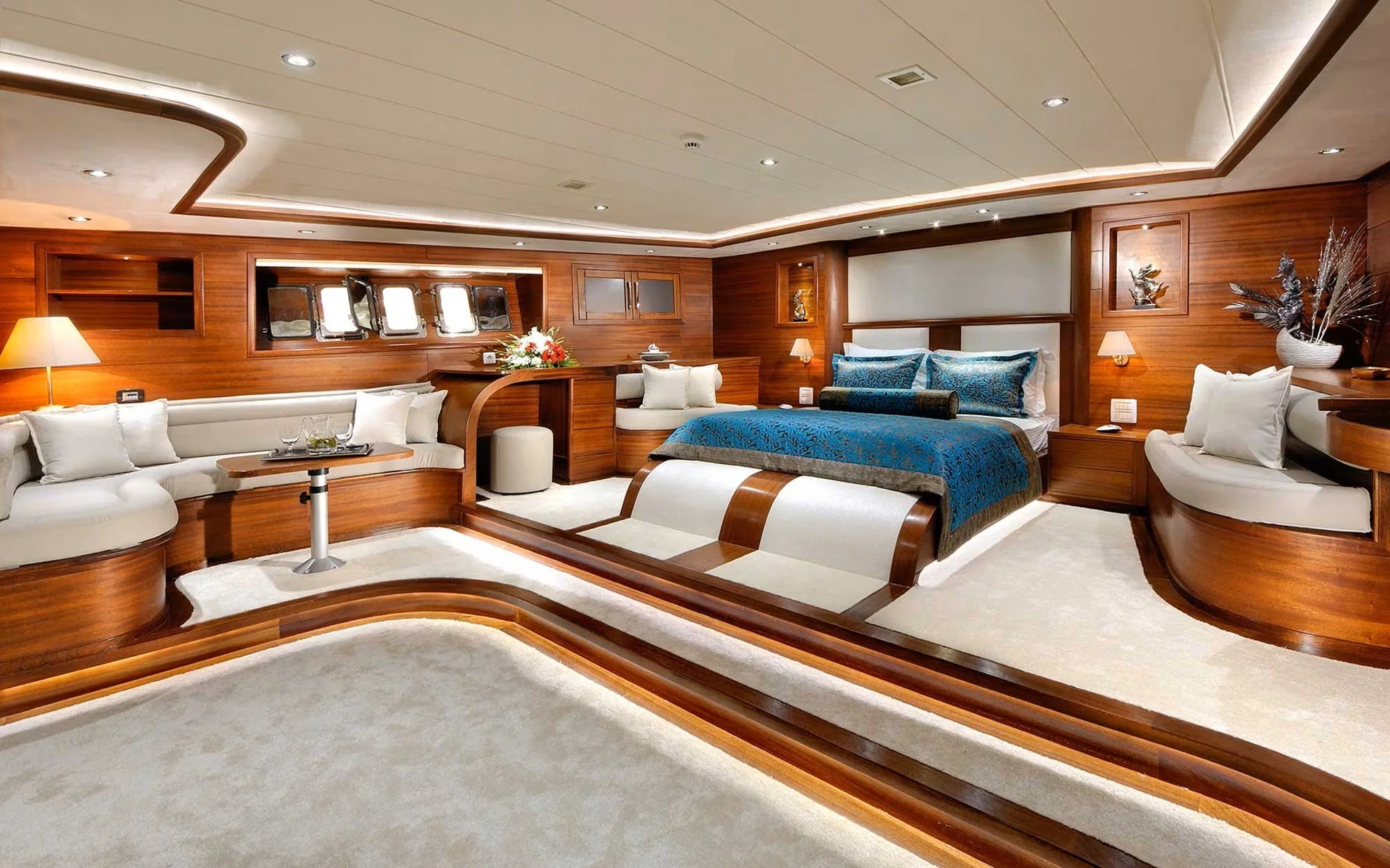 Luxurious cruise ship cabin with a large bed, seating area, and wooden interior decor.