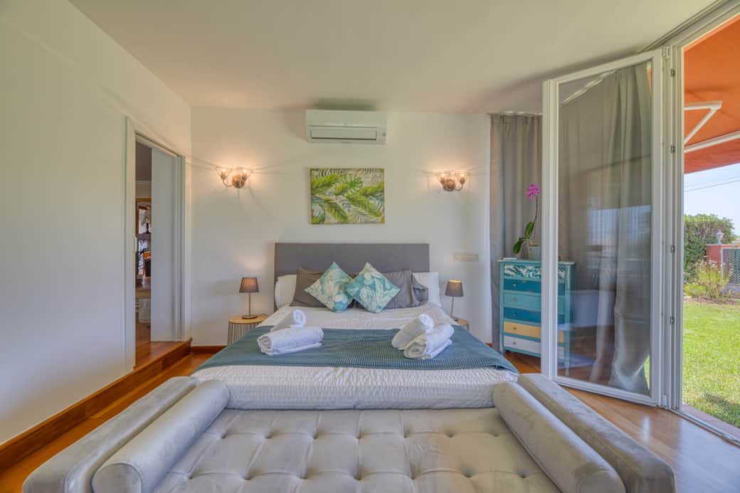 A bedroom with a bed, nightstands, lamps, and a sliding glass door leading to an outdoor area.