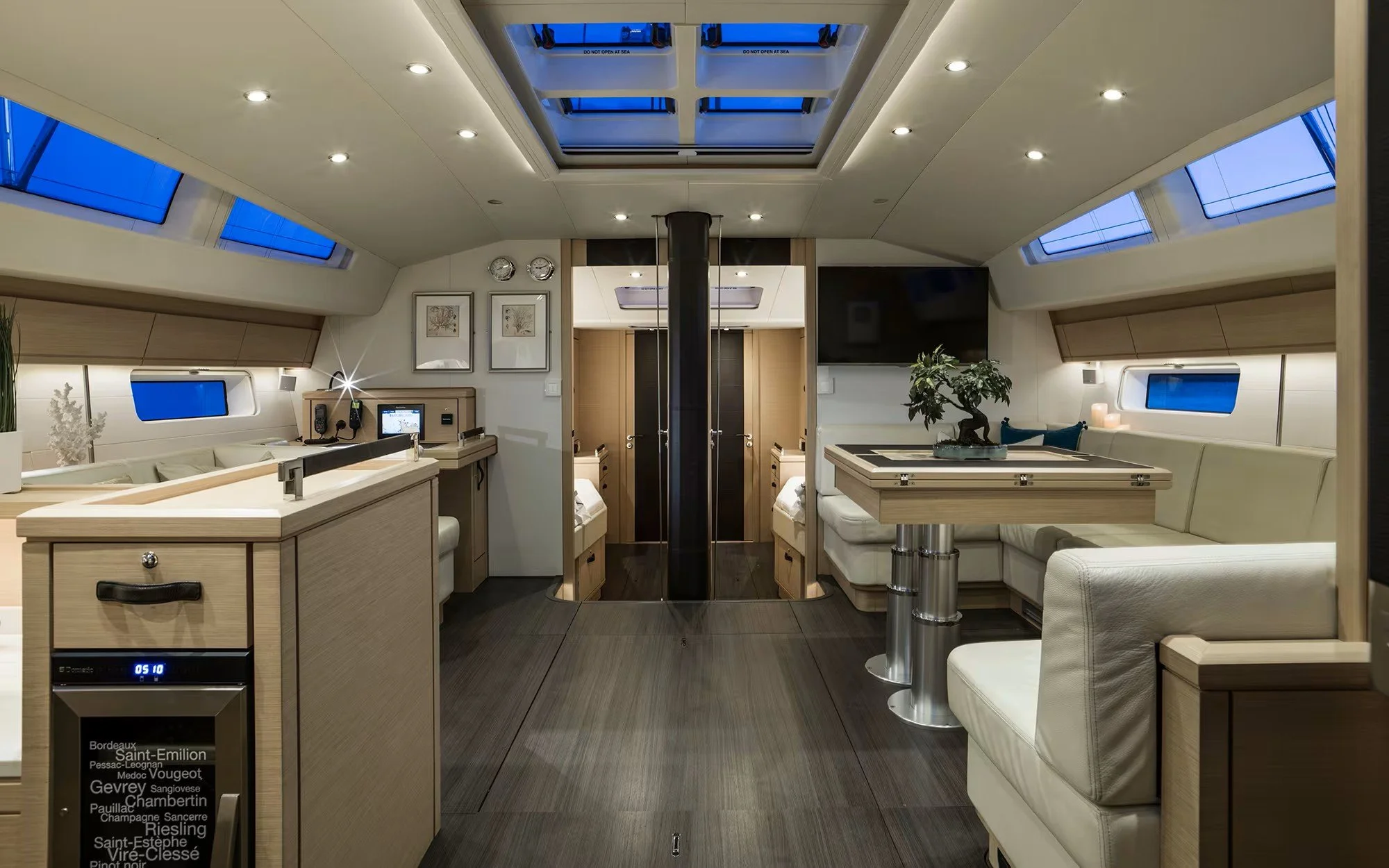 Interior of a luxury yacht with modern design, white leather seating, multiple windows, skylights, and a flat-screen TV.